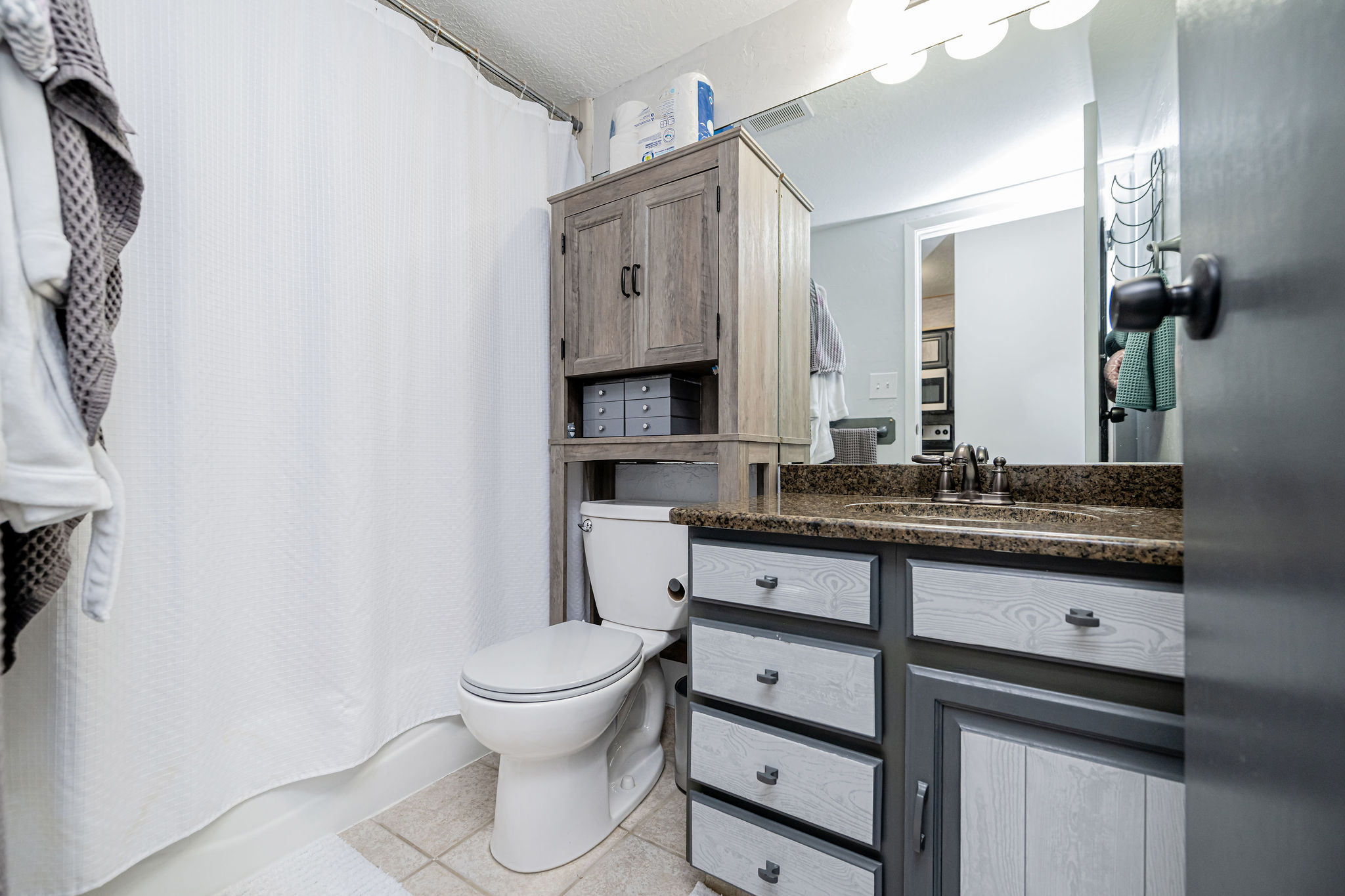 Bathroom featuring a vanity with a stone countertop, an integrated sink, and a wall-mounted mirror