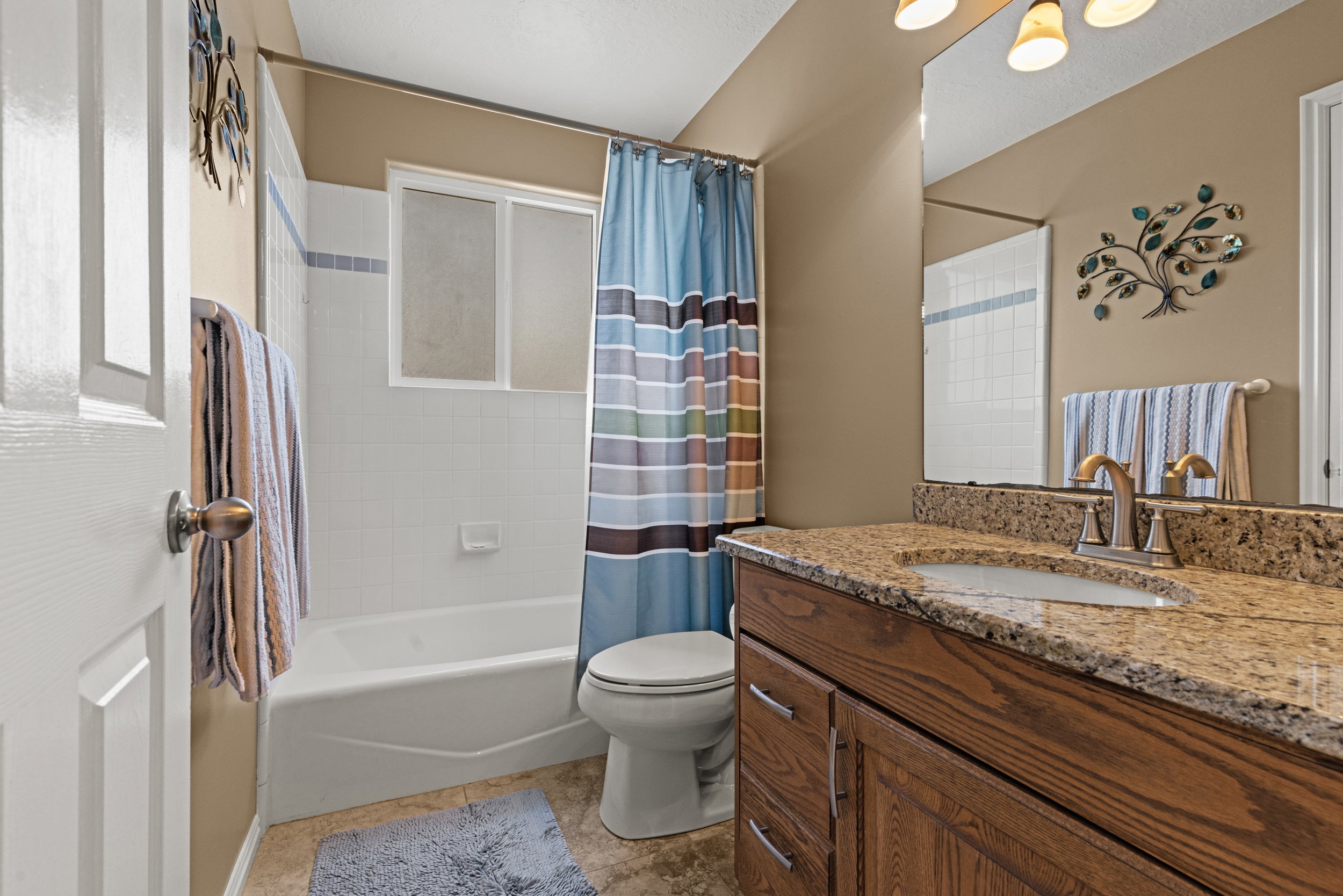 Bathroom featuring a wood-finish vanity with a granite countertop and an integrated sink