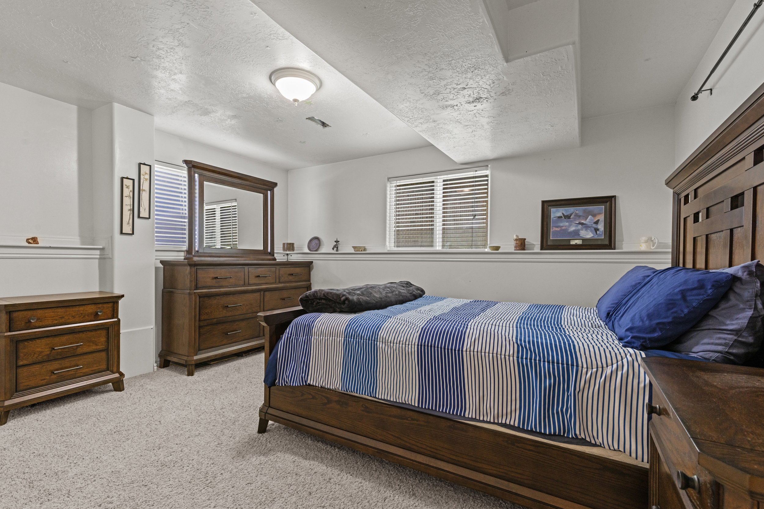 Carpeted room featuring a window with blinds, a built-in wall ledge, and a ceiling-mounted light fixture