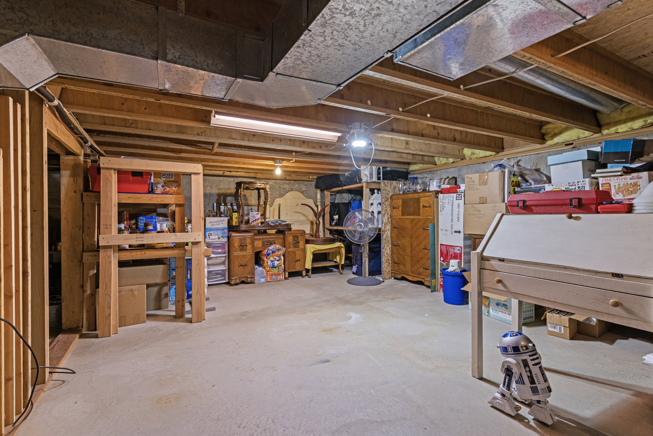 Unfinished basement featuring exposed wood joists, concrete flooring, exposed ductwork, and fluorescent lighting