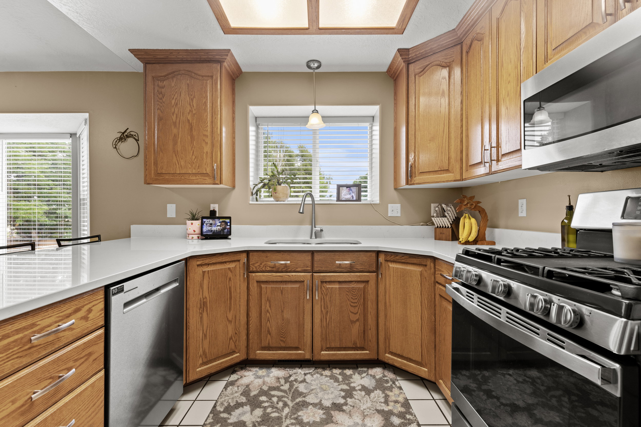 Kitchen featuring wood cabinetry, stainless steel appliances, white countertops, and a double basin sink