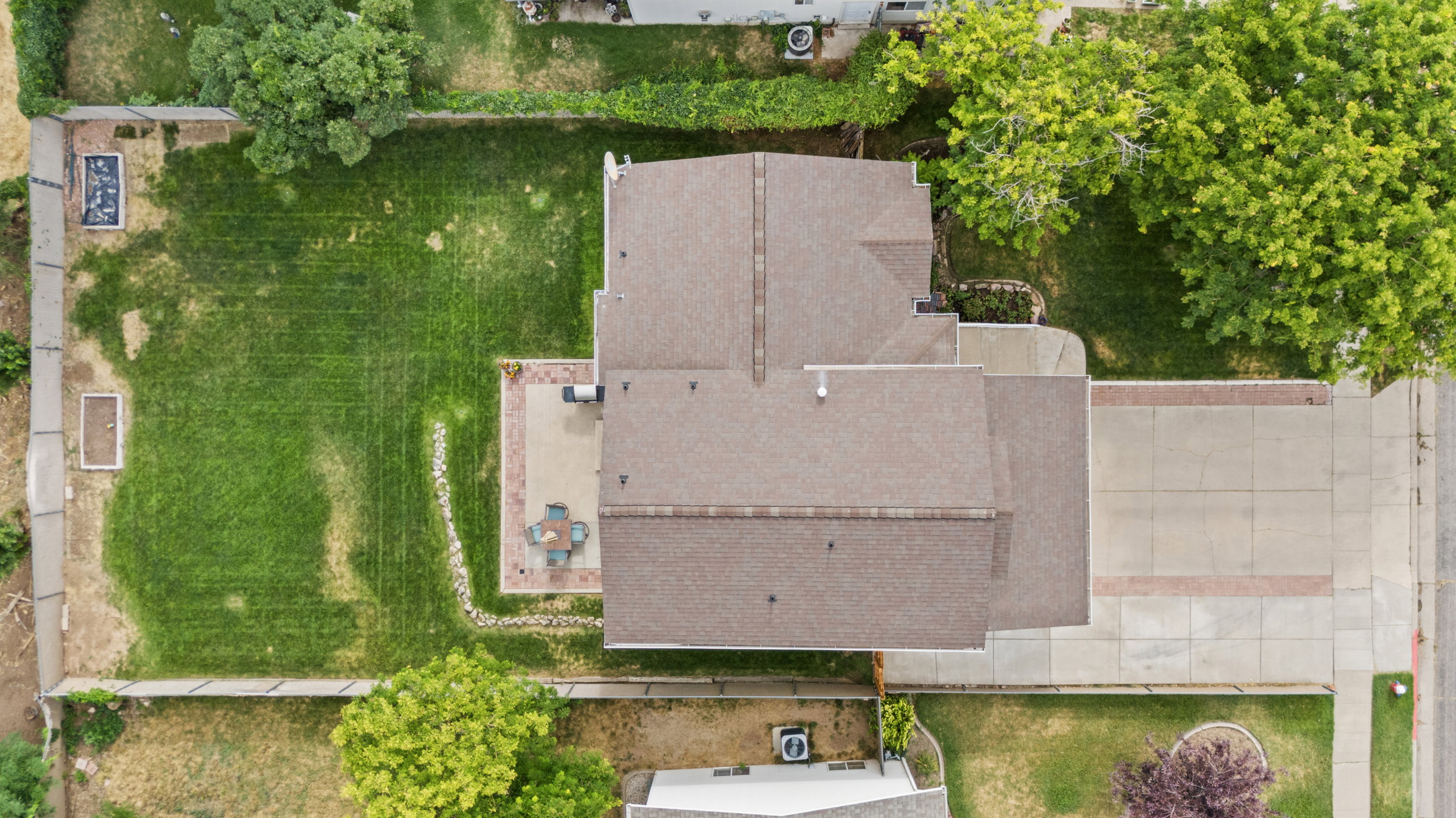 Spacious backyard featuring a brick paver patio, a manicured lawn, and raised garden beds