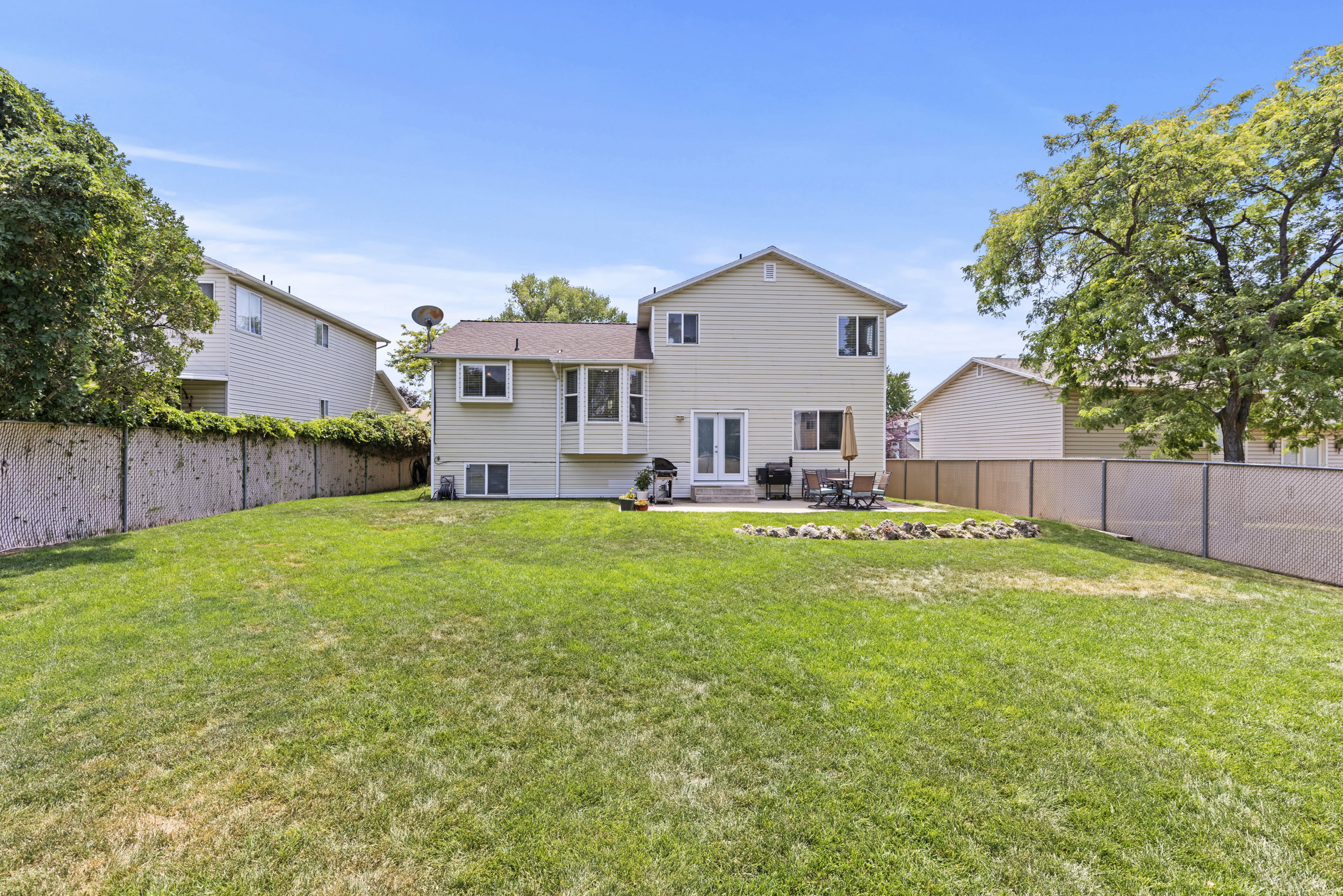 Expansive green lawn with a two-story residence featuring a ground-level patio
