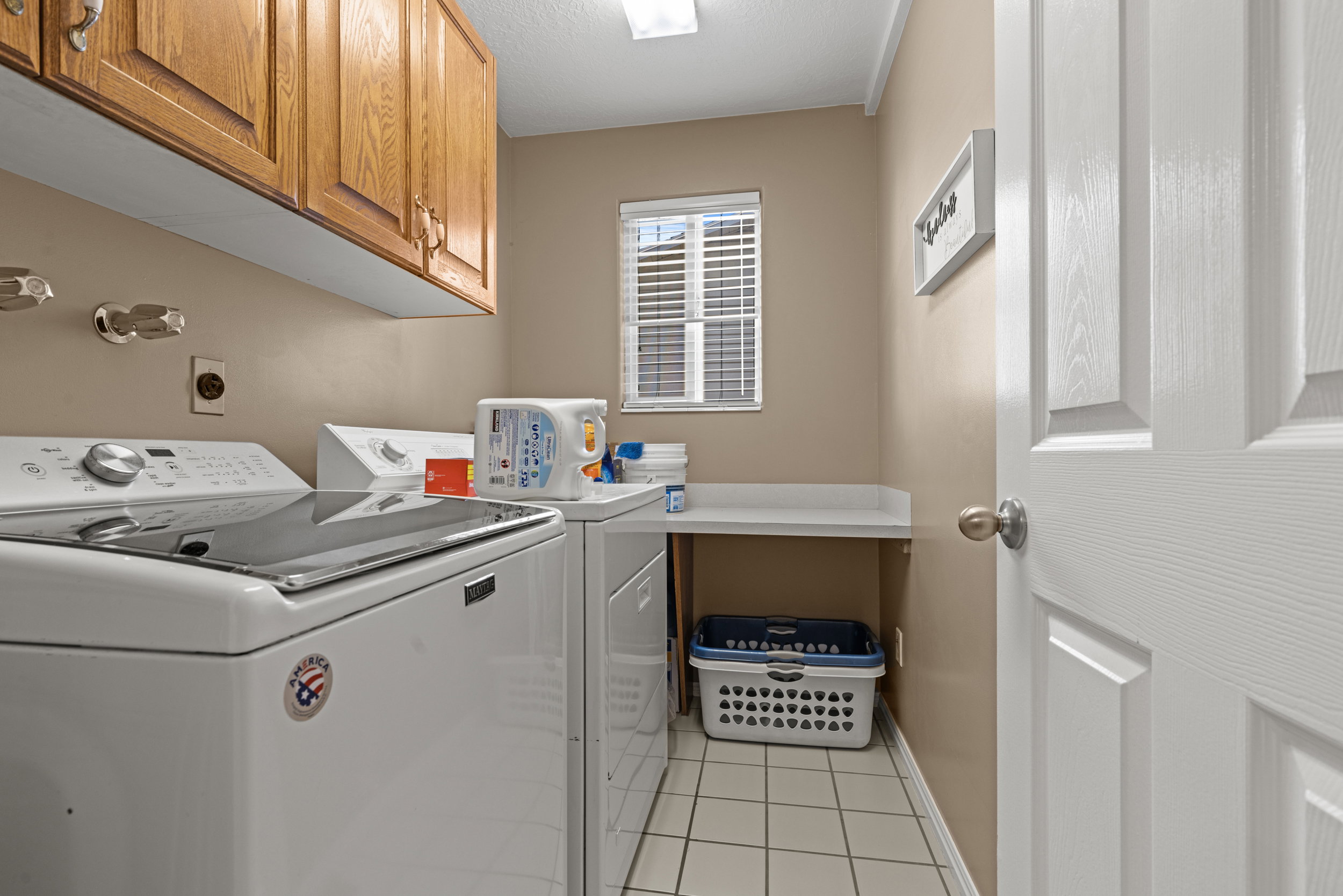 Dedicated laundry area featuring wood cabinetry, white appliances, and a built-in folding counter
