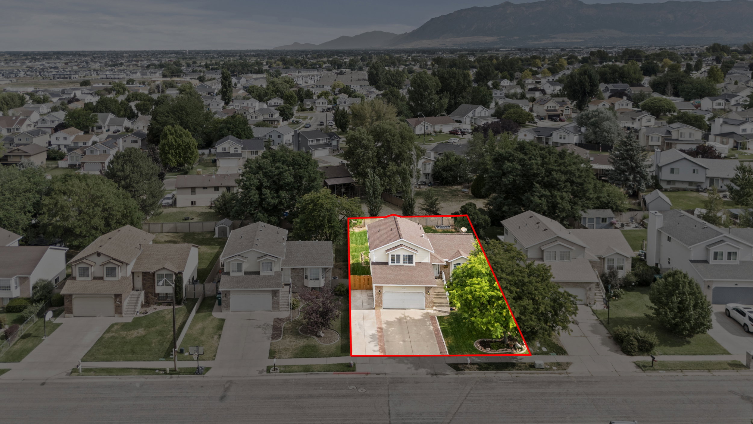 Two-story residence featuring a two-car garage, mature front yard landscaping, and a fenced backyard