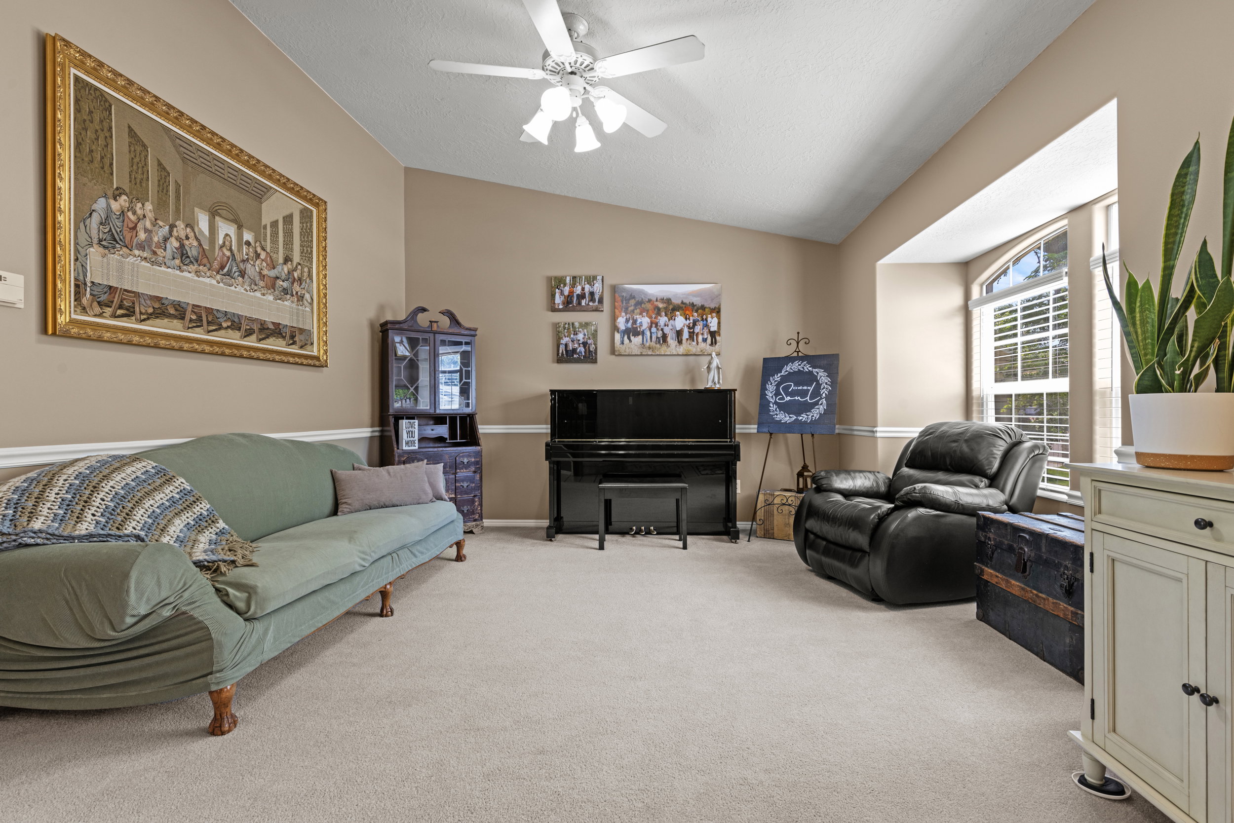 Spacious living area featuring vaulted ceilings, neutral paint tones, crown molding, and light-colored carpeting