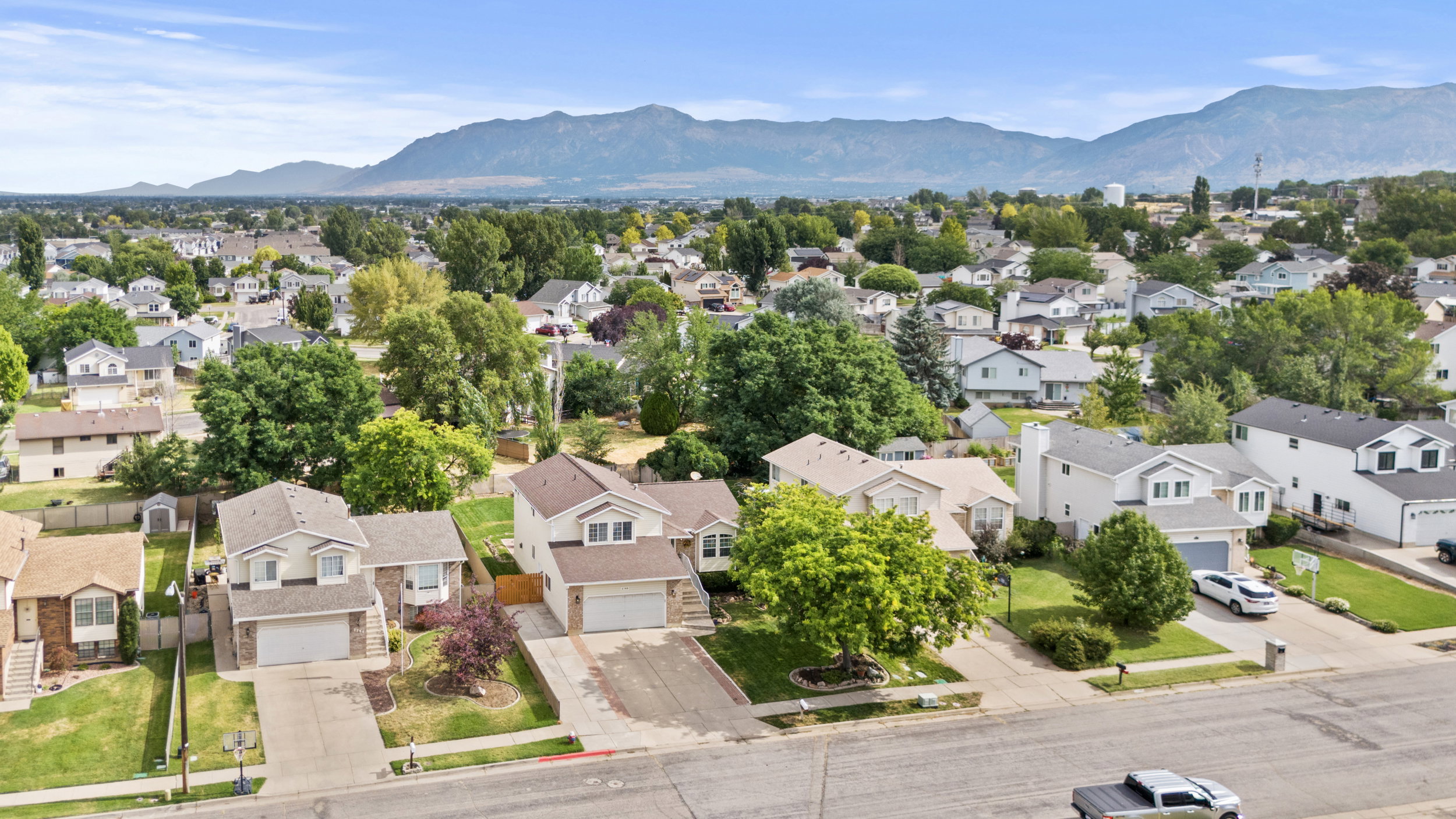 Residential neighborhood with a mountain backdrop, mature trees, and varied architectural styles