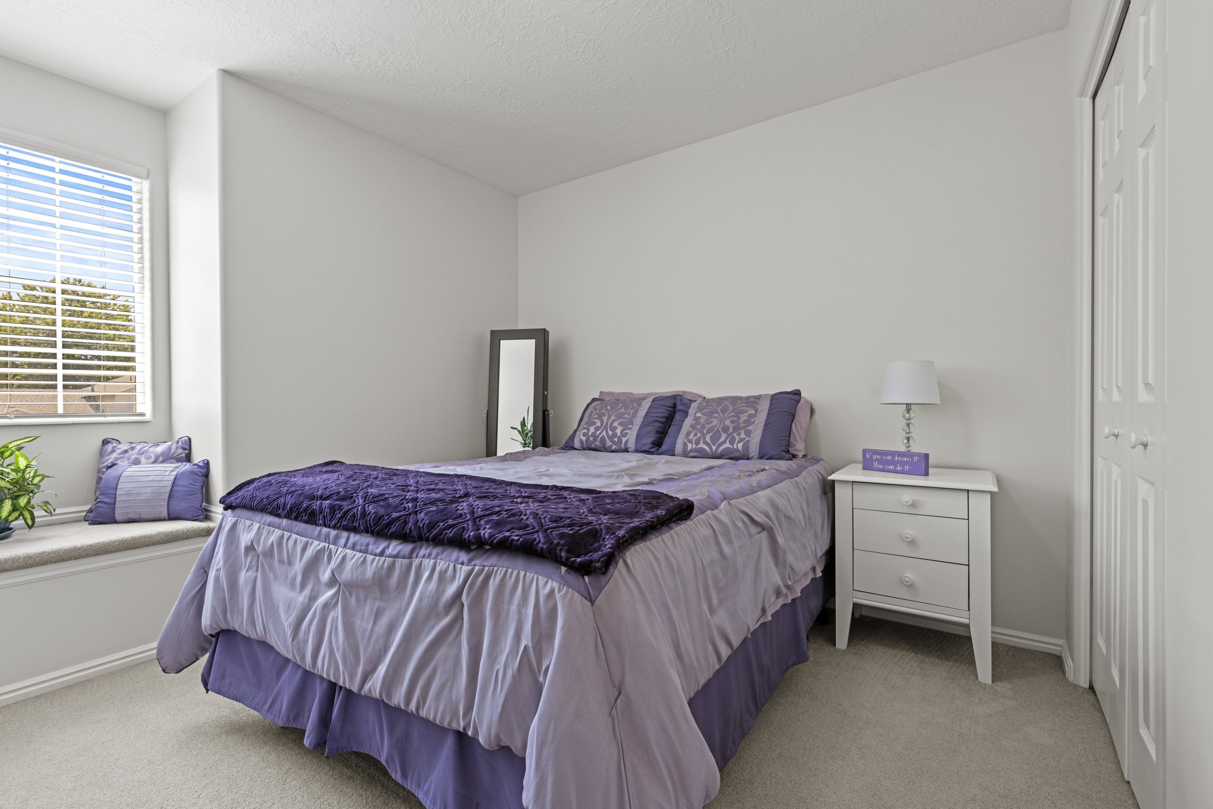 Bedroom featuring a large window with horizontal blinds, a built-in window seat, and carpet flooring