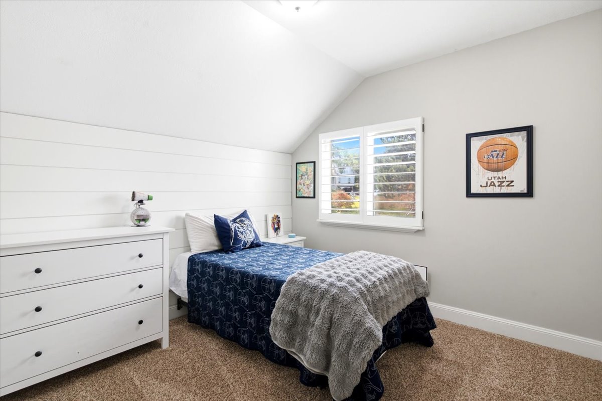 Bedroom featuring great lighting, neutral carpeting, and a window with plantation shutters