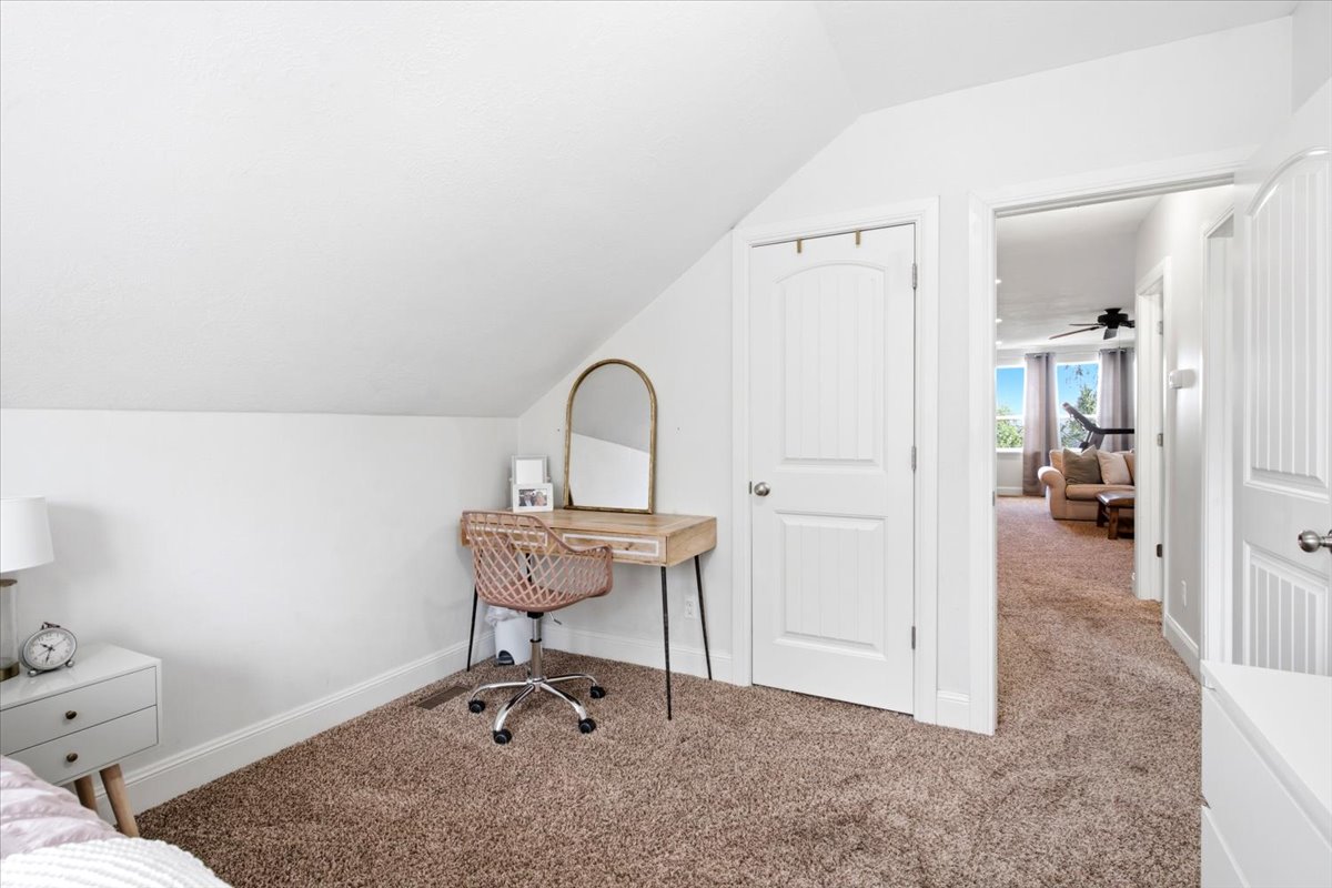 Room featuring angled white walls, brown textured carpeting, and white baseboards