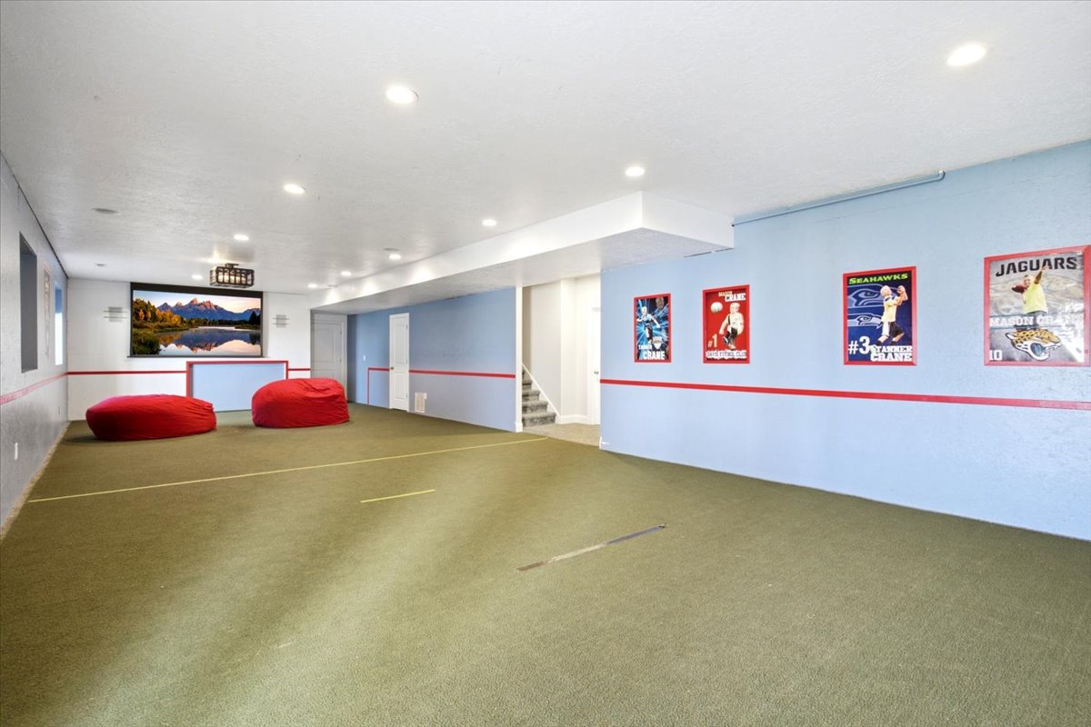 Spacious lower-level room featuring recessed lighting, light blue and gray painted walls with a red accent stripe, and turf flooring