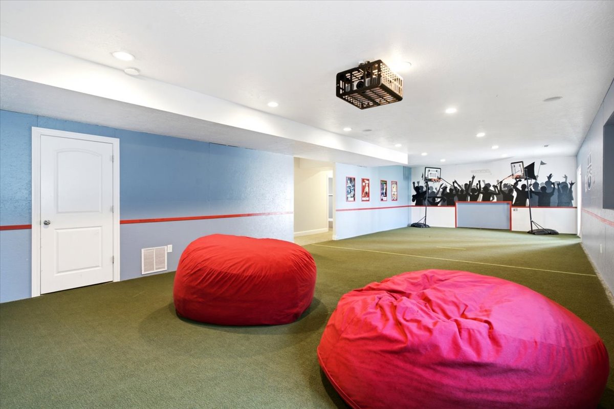 Expansive room featuring green carpet flooring, recessed lighting, and a projector mount