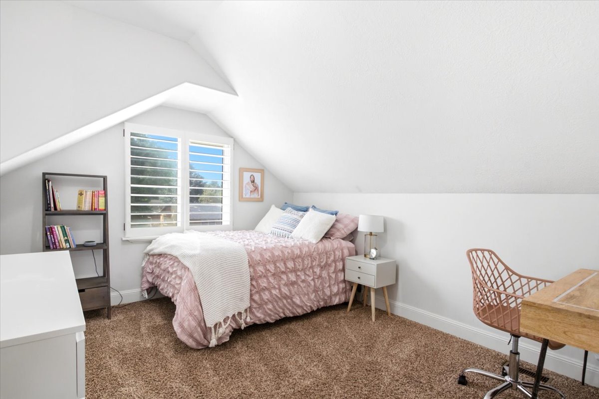 Attic room with sloped ceilings, carpet flooring, a multi-pane window with louvered shutters, and white baseboards