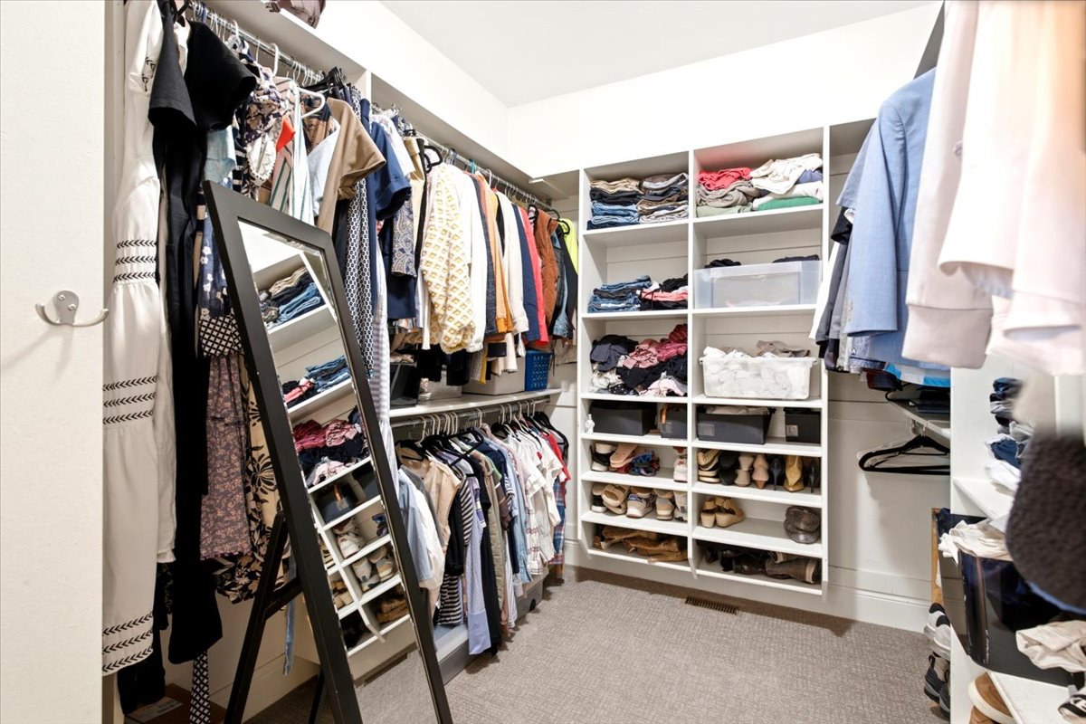 Customizable walk-in closet featuring built-in shelving, hanging rods, and carpet flooring