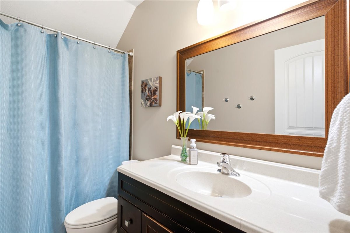 Bathroom featuring a dark wood vanity with white countertop, integrated sink, and an expansive wood-framed mirror