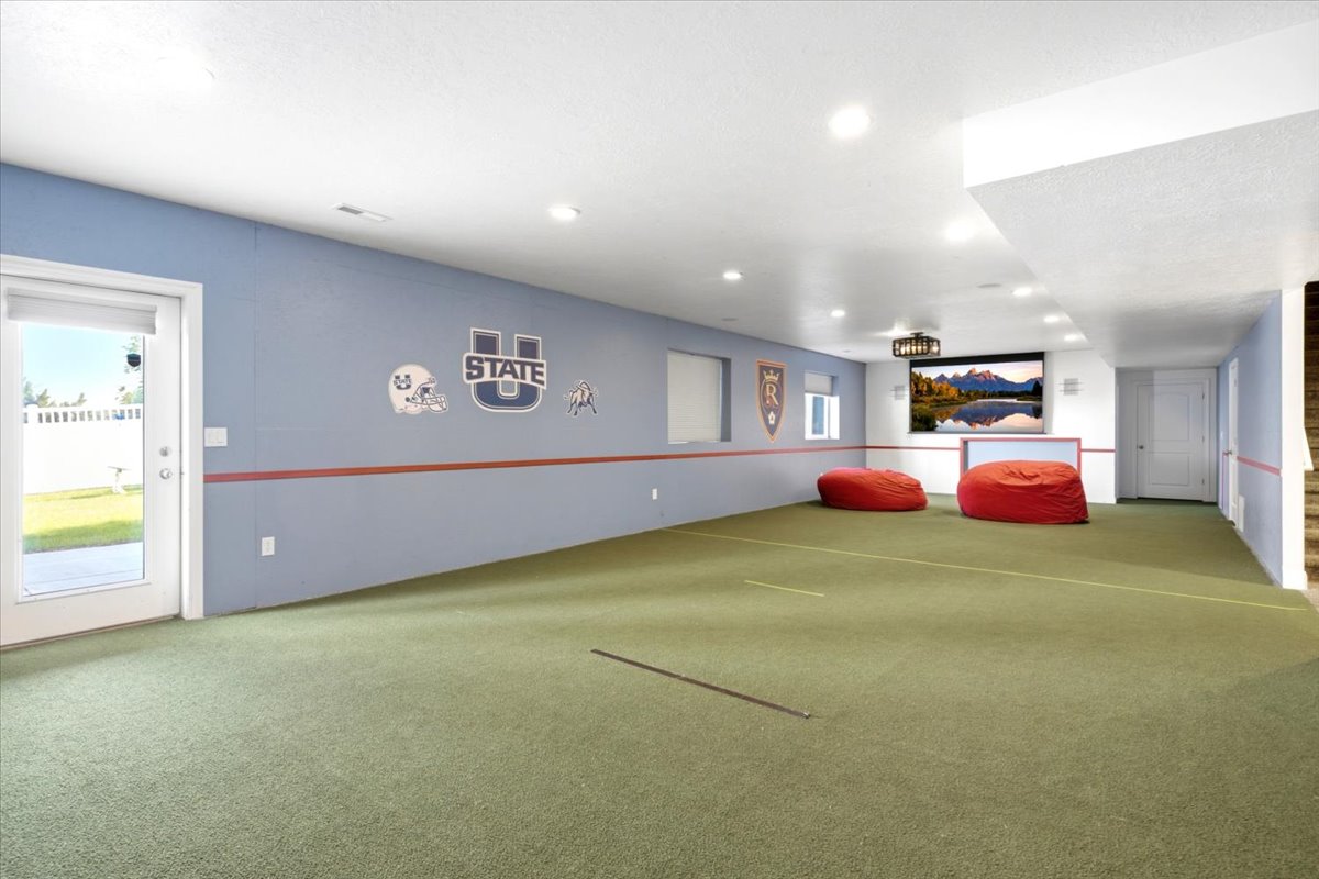 Versatile room featuring light blue and white painted walls, plumbed for a future kitchen, recessed lighting, and a screen projector with integrated speakers