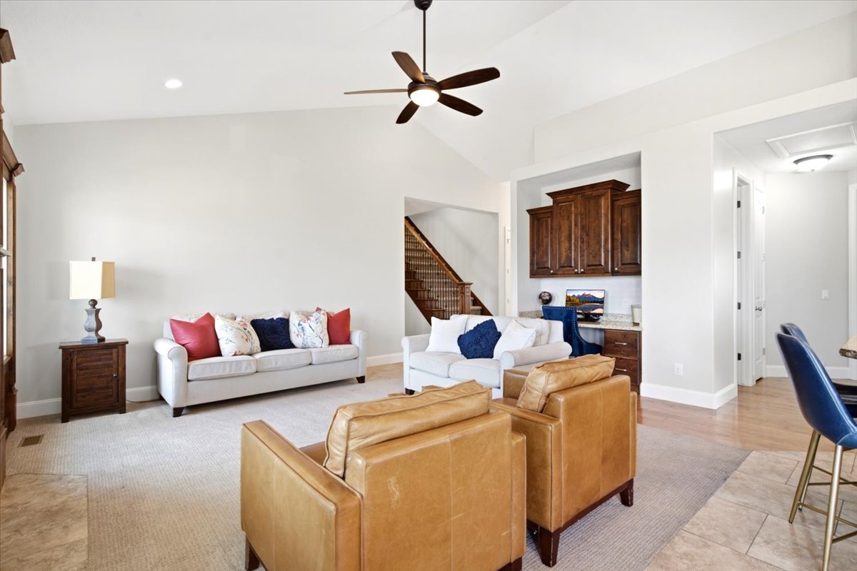 Spacious living area featuring a vaulted ceiling and a ceiling fan