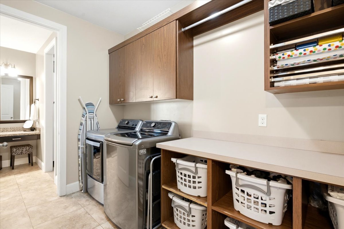 Dedicated laundry area featuring upper cabinetry, a hanging rod, and built-in shelving with a countertop workspace