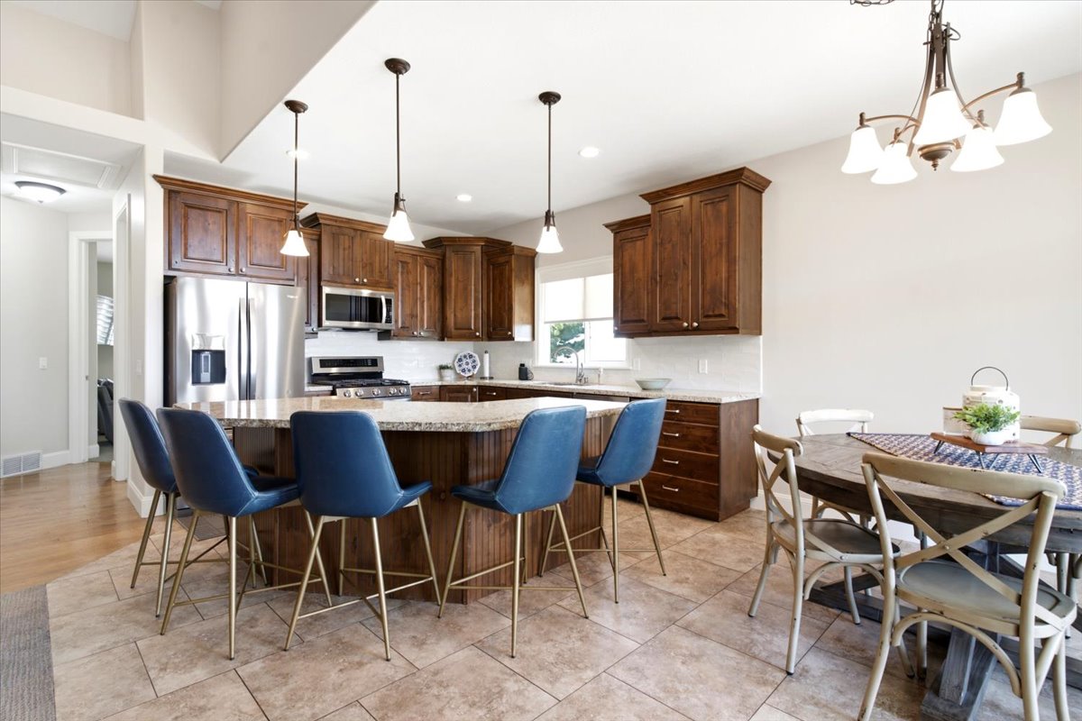 Spacious kitchen featuring a large island with a granite-finish countertop, stainless steel appliances, including double ovens, and abundant wood cabinetry