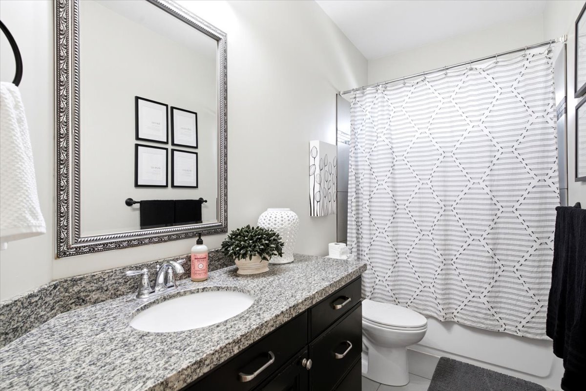 Bathroom featuring a spacious vanity with a granite countertop, undermount sink, and dark wood cabinetry
