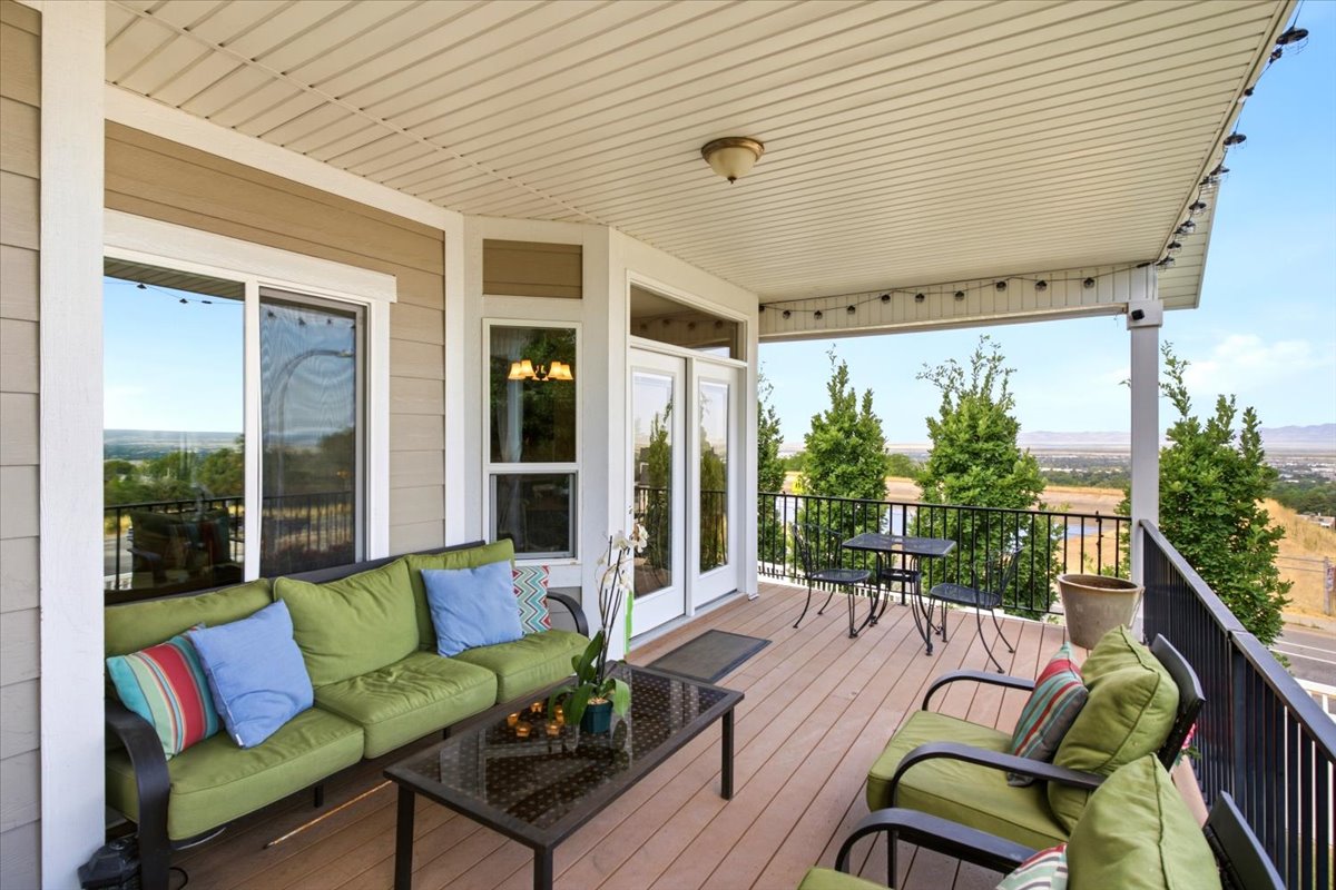 Spacious covered deck with wood-finish flooring, white vinyl soffit, and black metal railings