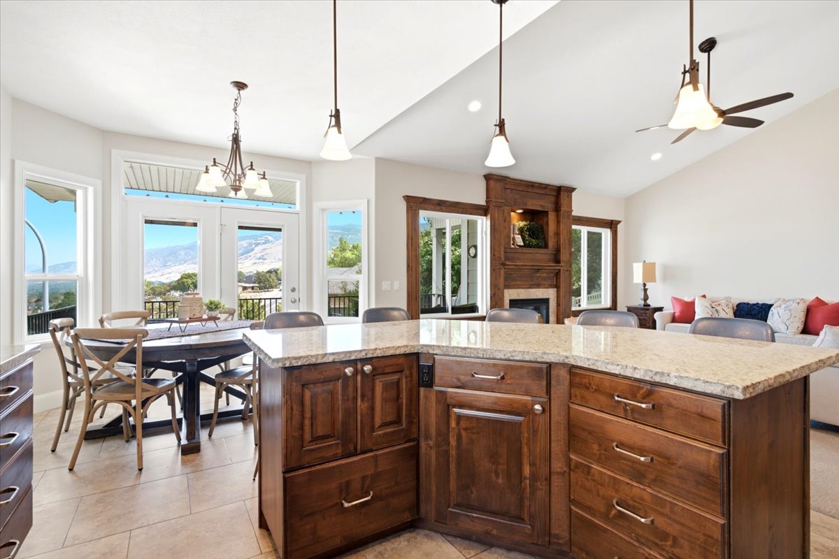 Open-concept interior featuring a substantial kitchen island with a light-toned countertop, rich wood-finish cabinetry, and contemporary pendant lighting