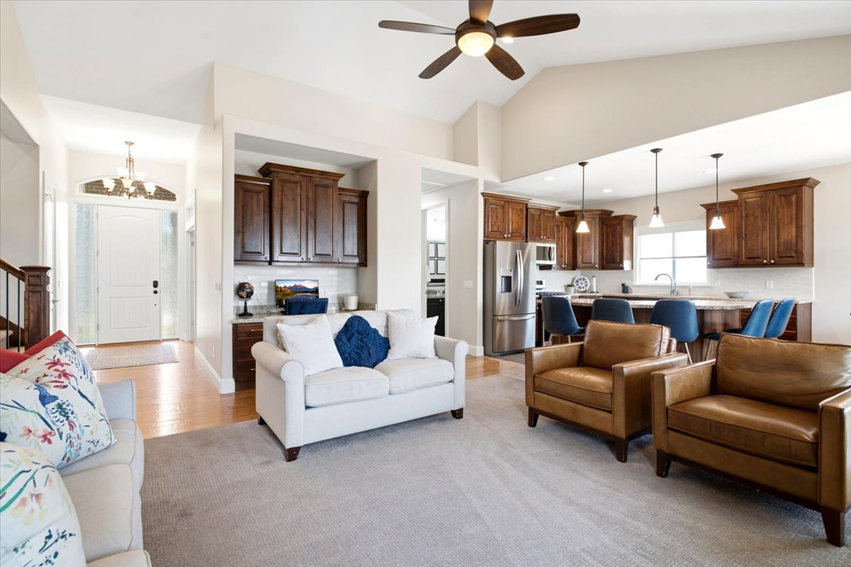 Open concept living area featuring vaulted ceilings, wood-finish flooring, and a ceiling fan