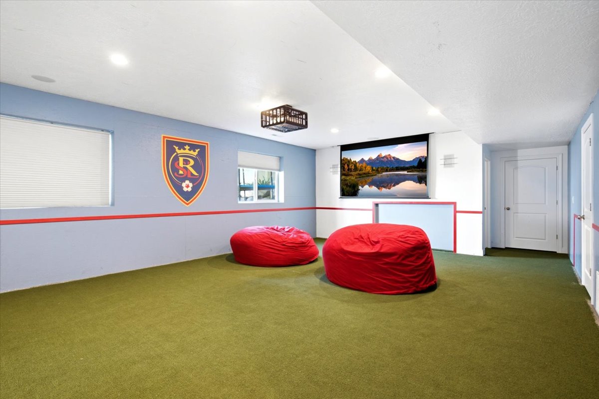 Entertainment room featuring a large projector screen, recessed lighting, and wall-mounted speakers