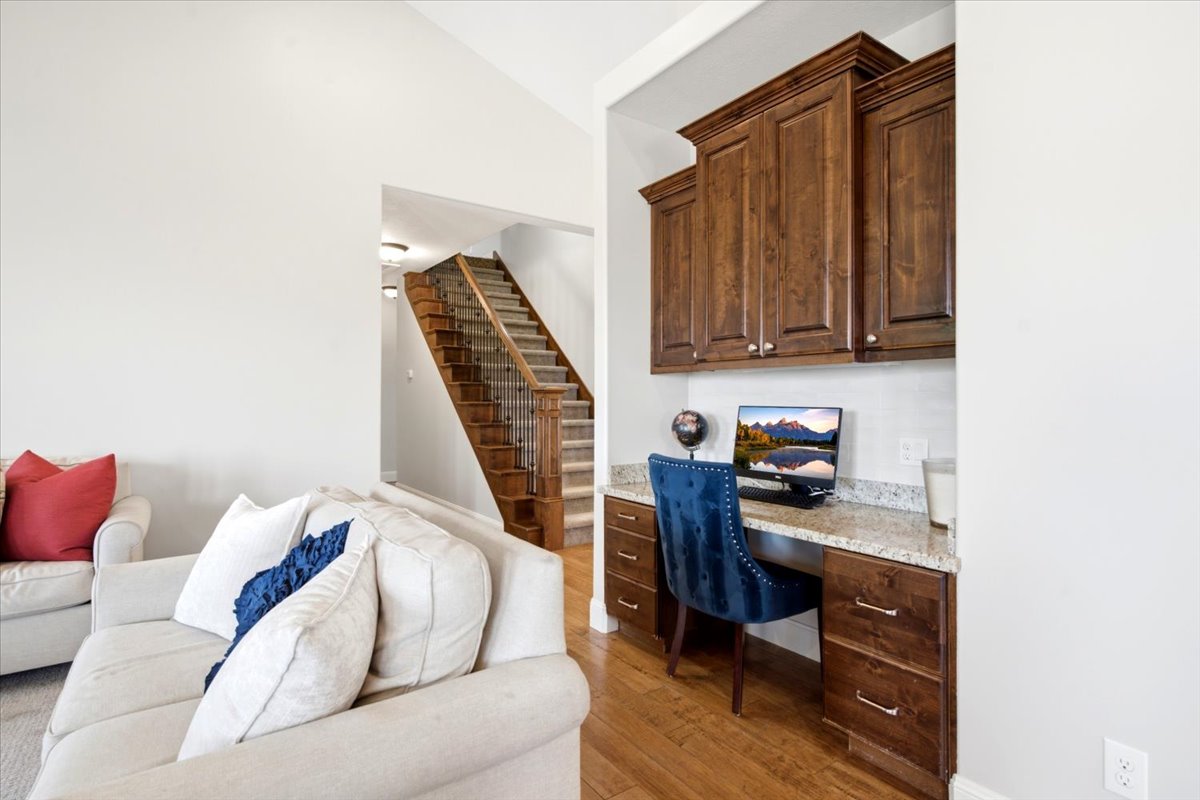 Built-in desk with wood-finish cabinetry, granite-style countertop, and tile backsplash