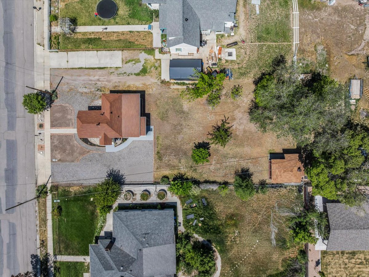 Aerial perspective showcasing a property with a brown-roofed structure and a gravel-paved driveway