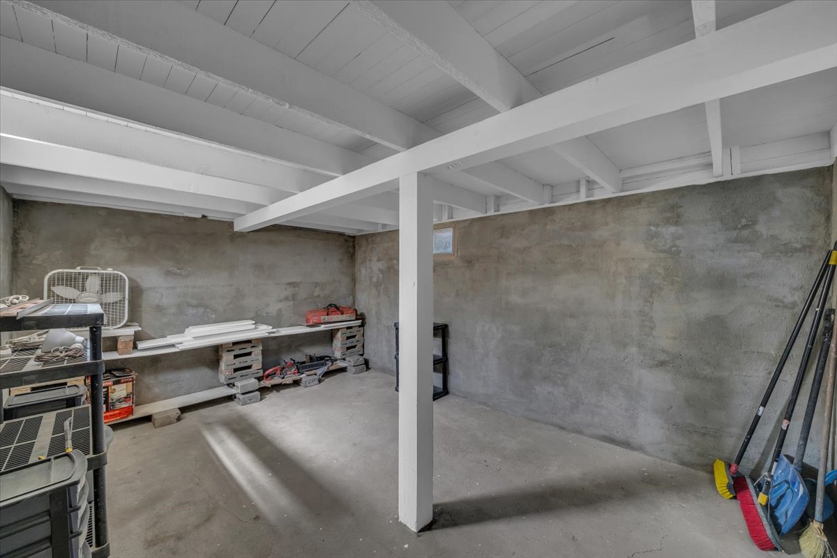 Spacious utility room featuring a painted beam ceiling, concrete flooring, and exposed concrete walls