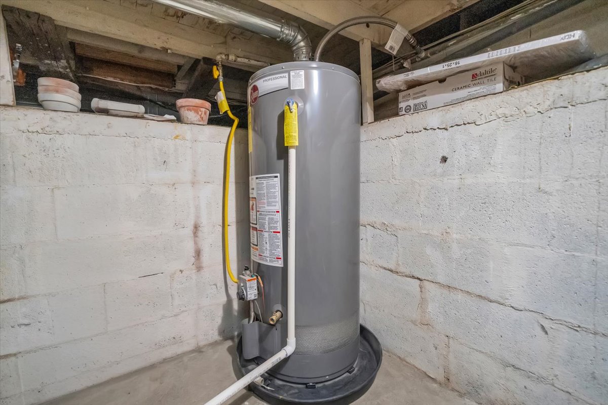 Utility room featuring a professional-grade water heater and exposed ceiling joists