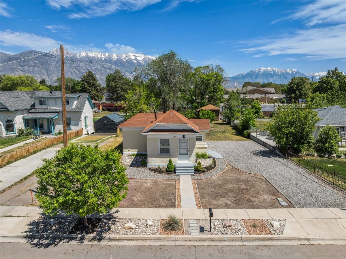 A single-story residence with a red-shingled hip roof and light-colored stucco exterior