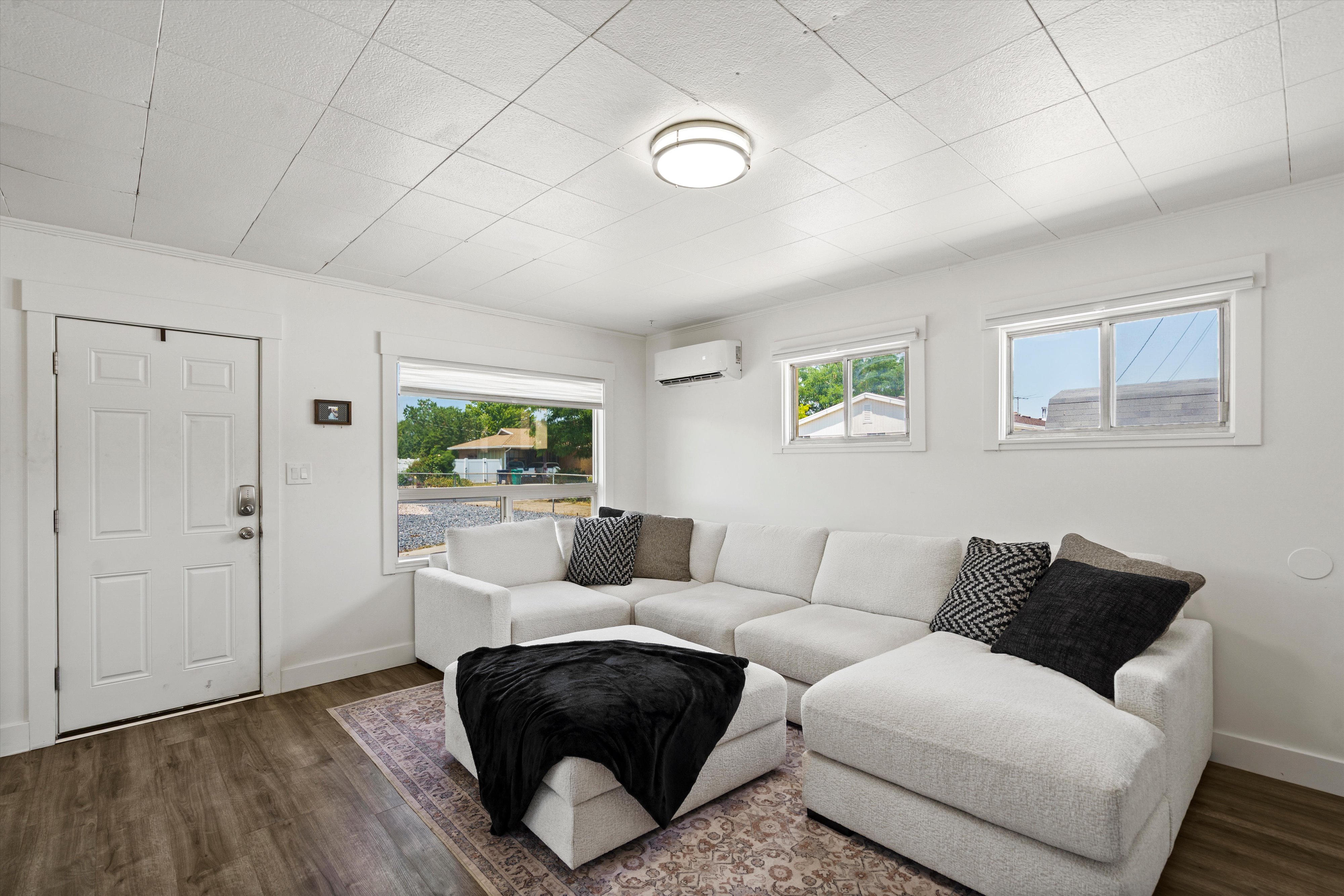 Bright room featuring wood-finish flooring, white walls, and a white paneled entry door