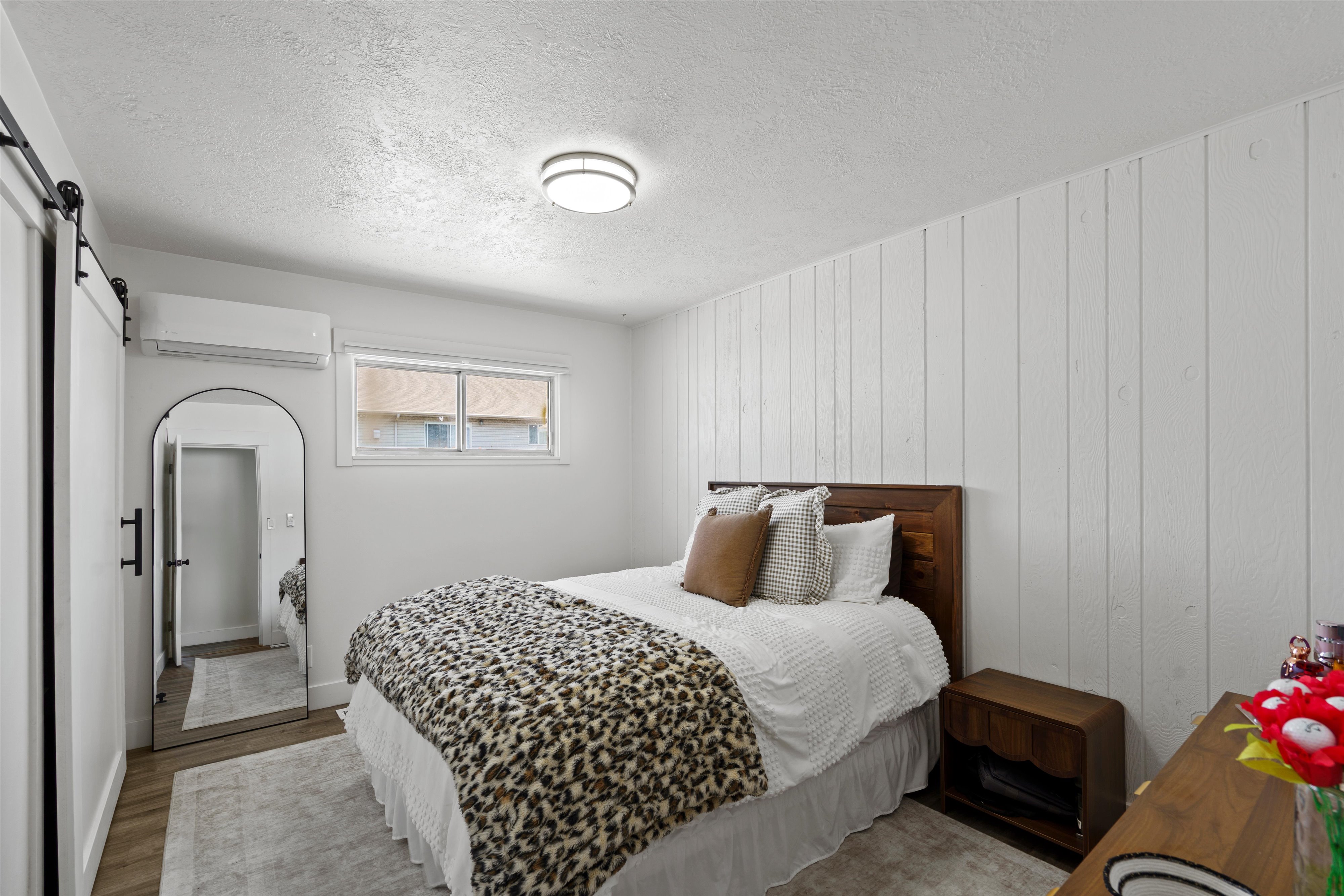 Bedroom featuring a white shiplap accent wall and wood-finish flooring