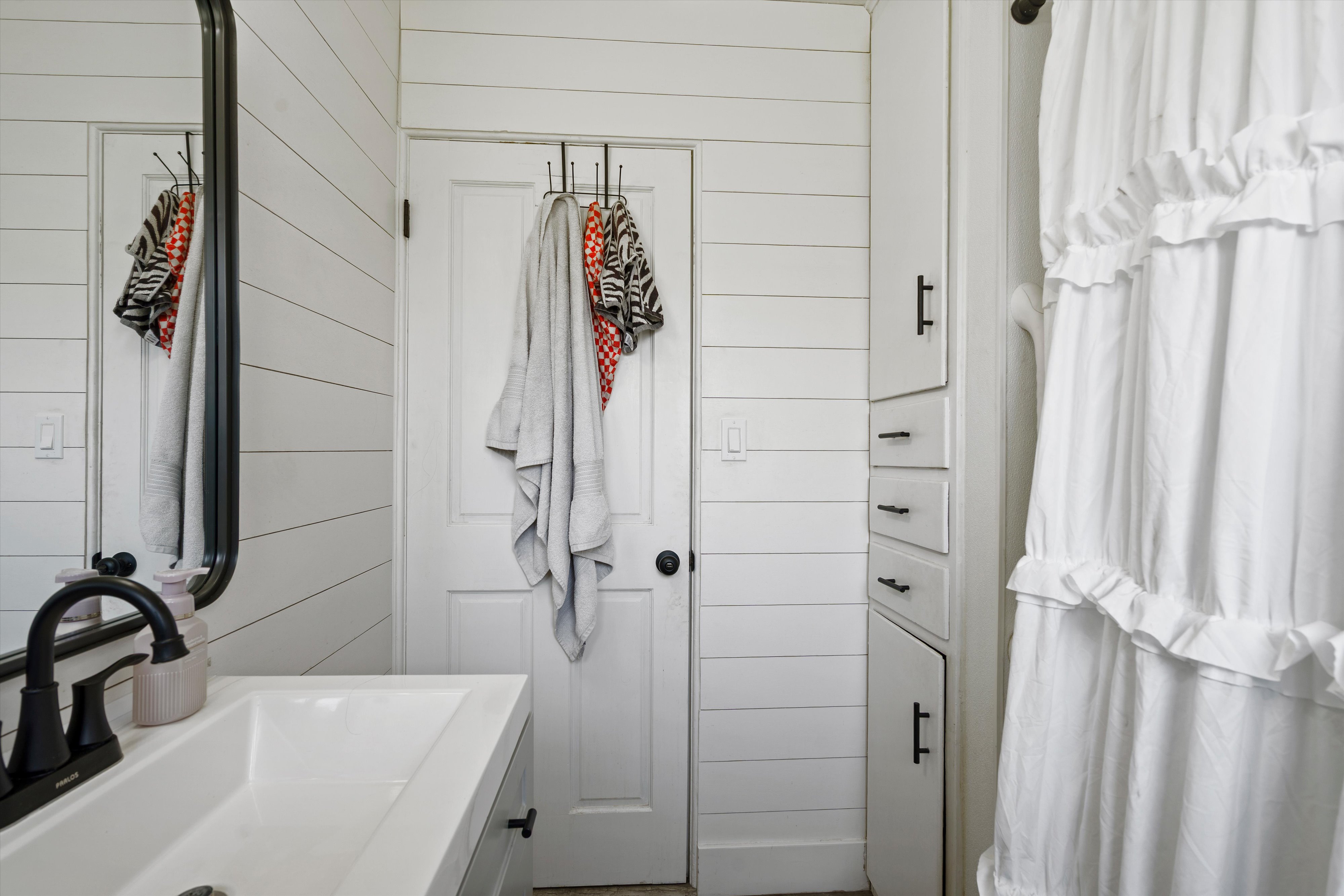 Bathroom featuring shiplap walls and built-in storage cabinetry