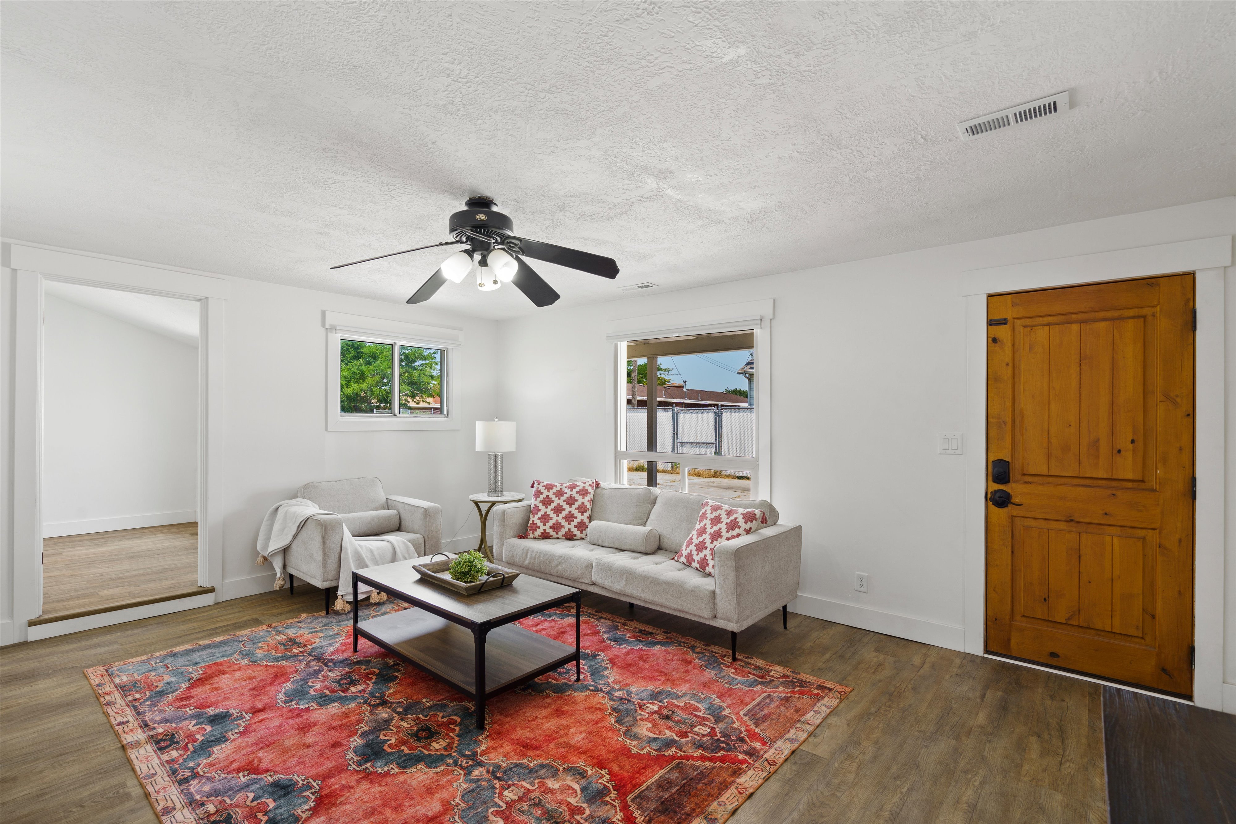 Bright living area featuring wood-finish flooring, white walls, and a ceiling fan