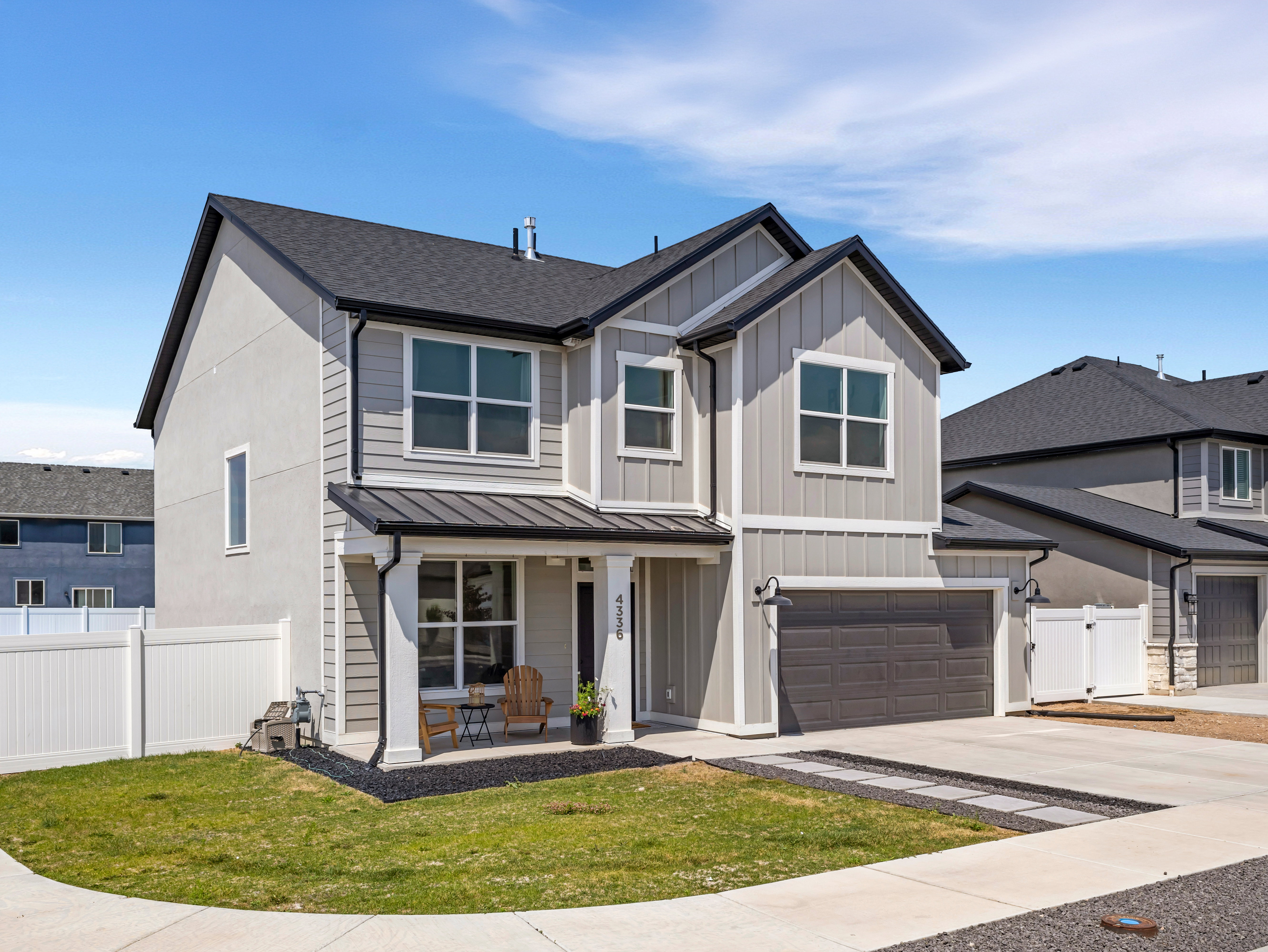 Contemporary two-story residence with a gray exterior, black asphalt shingle roof, and white trim accents