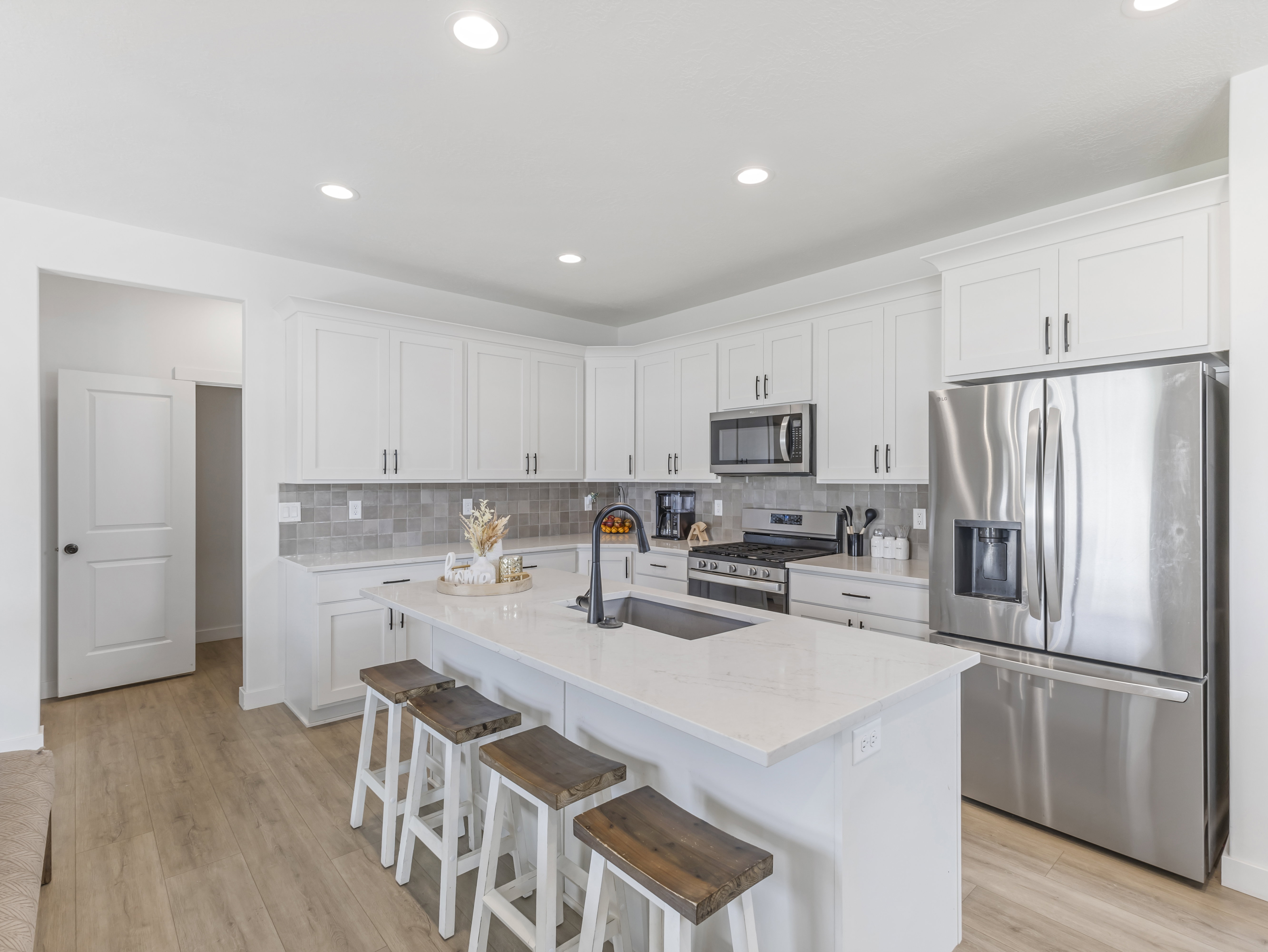 Contemporary kitchen featuring white cabinetry, stainless steel appliances, and a central island with a sink