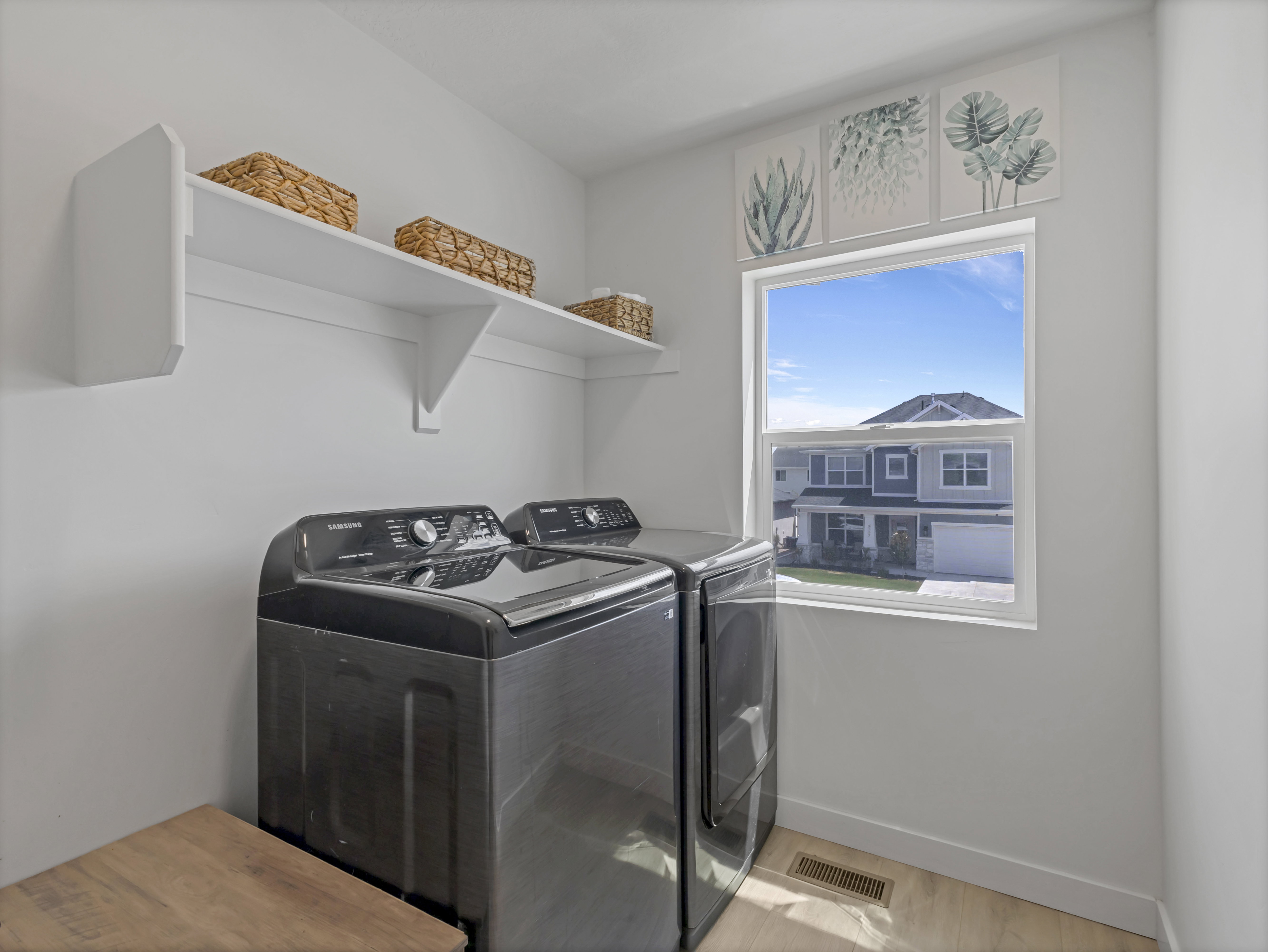 Dedicated laundry area featuring a window, overhead shelving, and wood-finish flooring