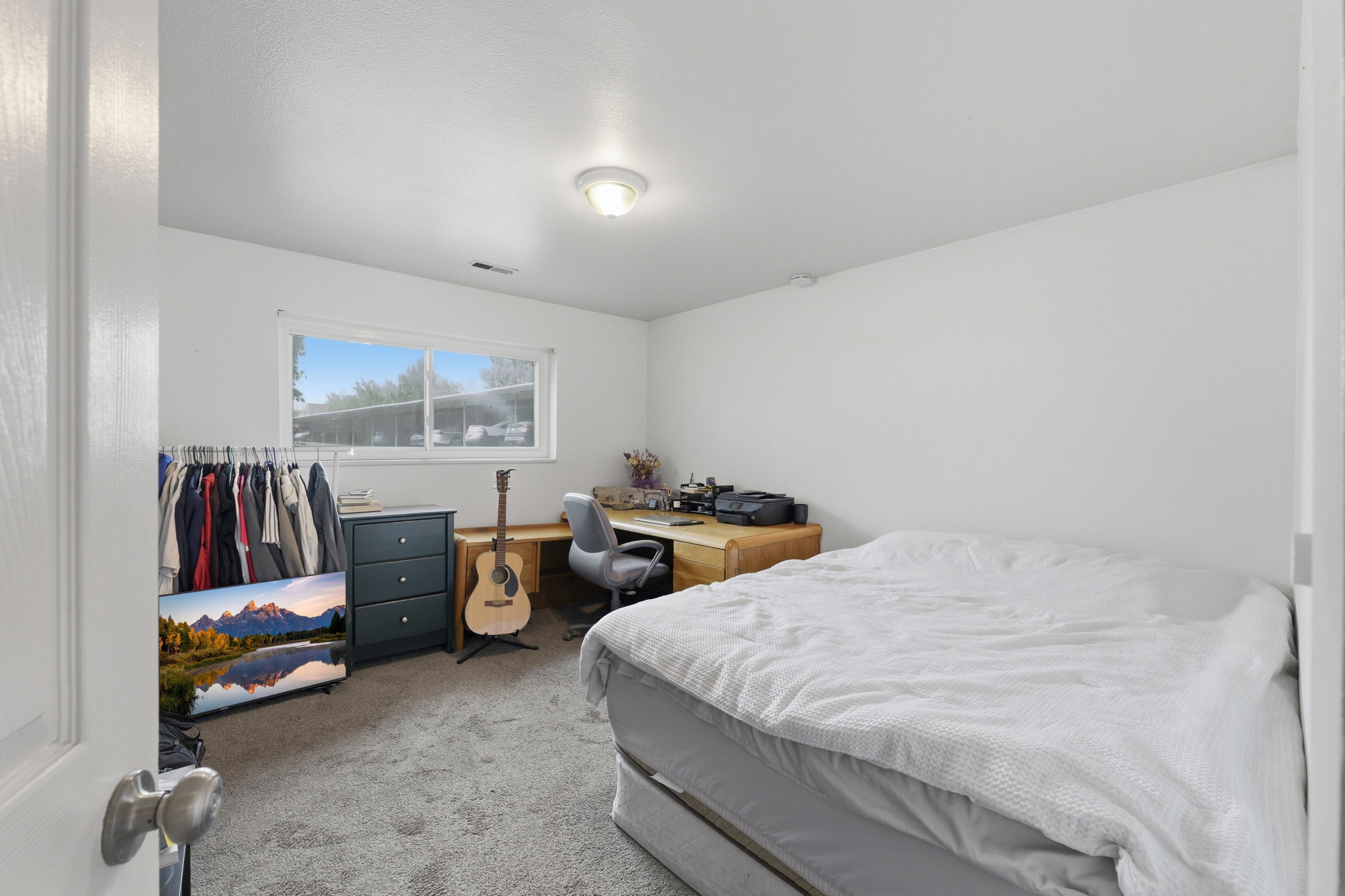 Carpeted room featuring a white ceiling and walls, a window with horizontal blinds, and a flush-mount ceiling light fixture
