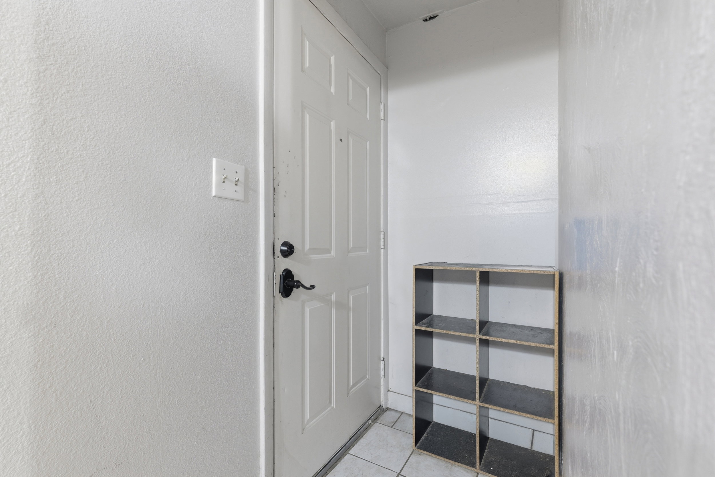 Entryway featuring a paneled door with dark hardware, light-colored walls, and tile flooring