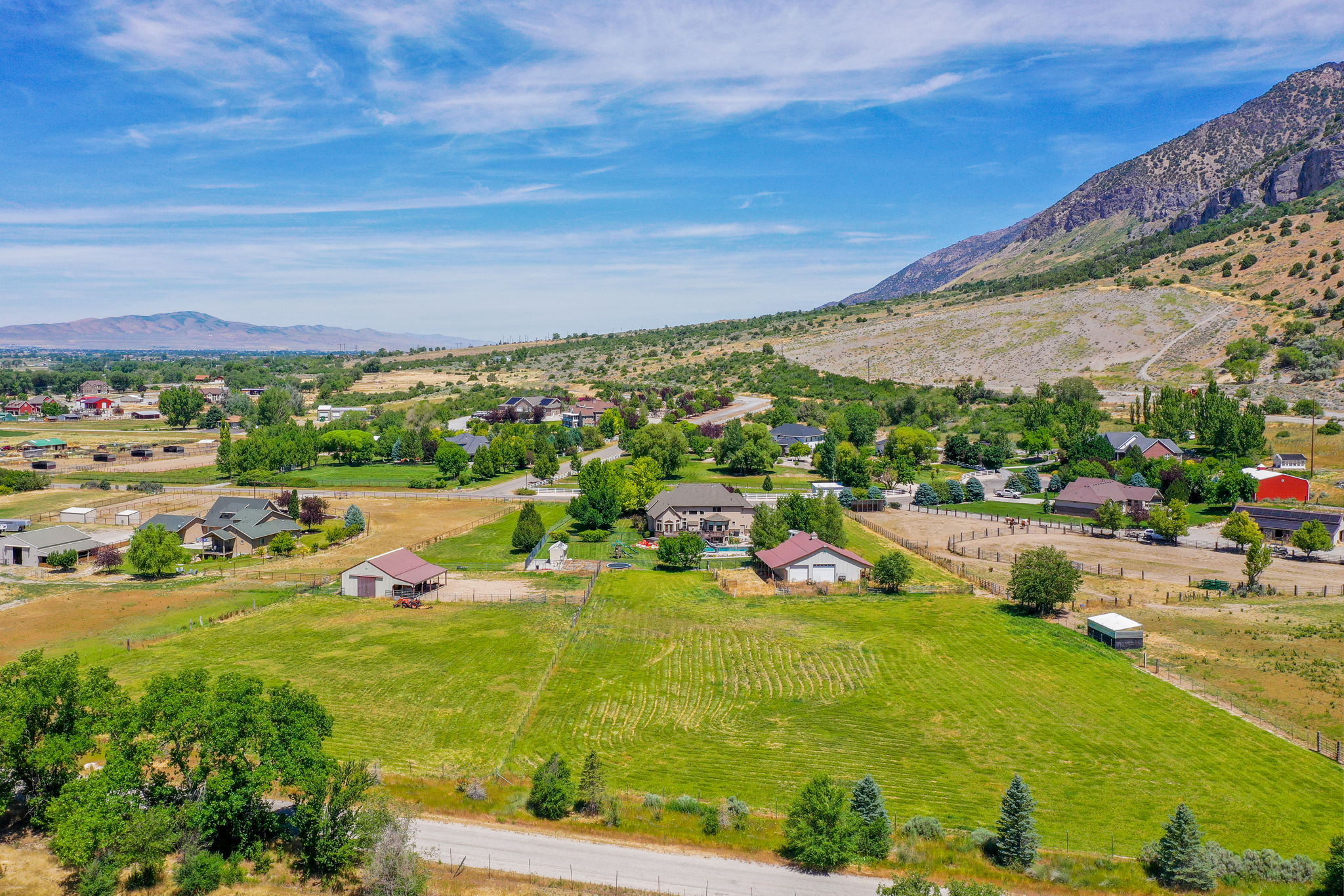 Expansive property featuring verdant fields, a mountainous backdrop, and mature trees