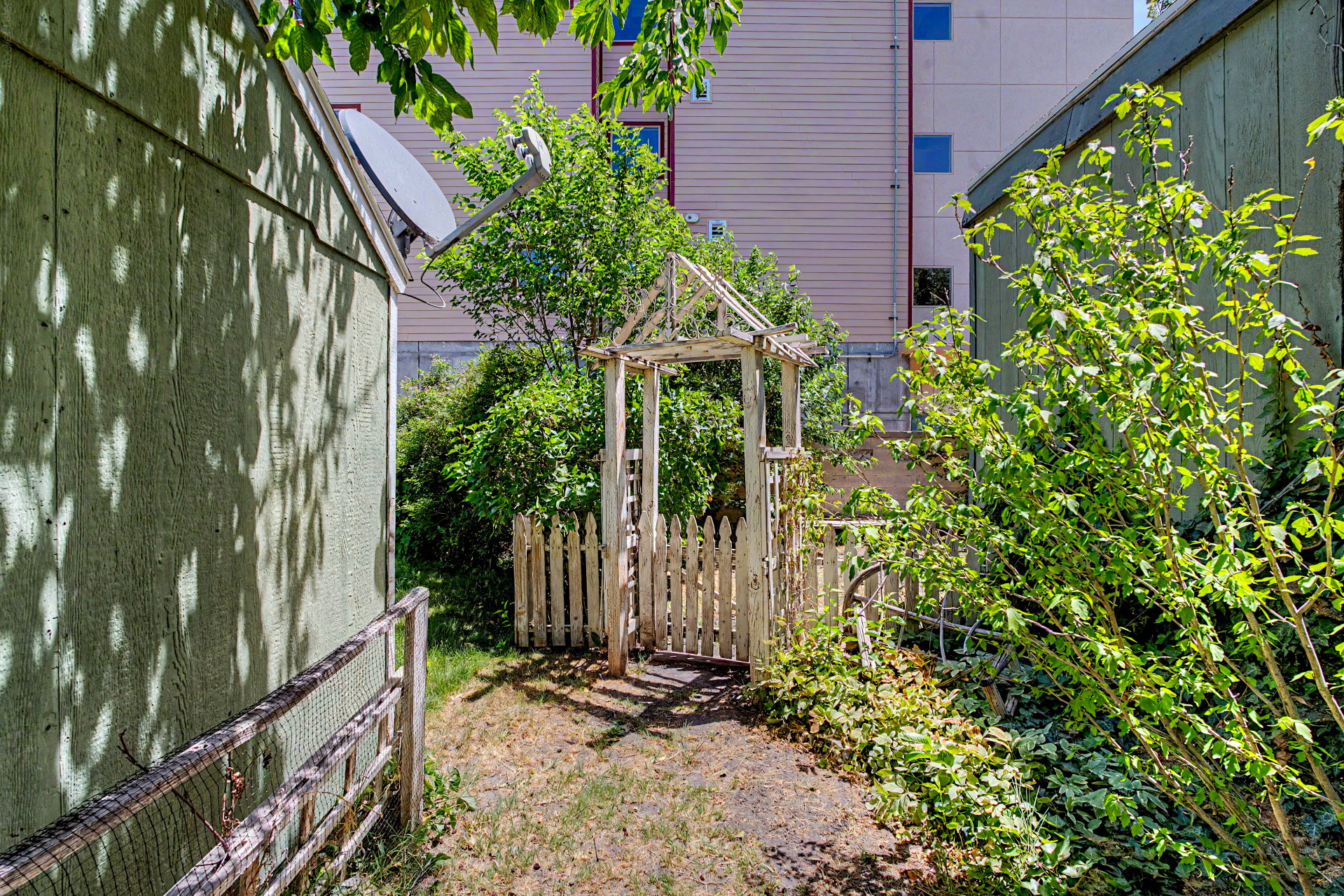 Gated garden entry with picket fence and mature foliage