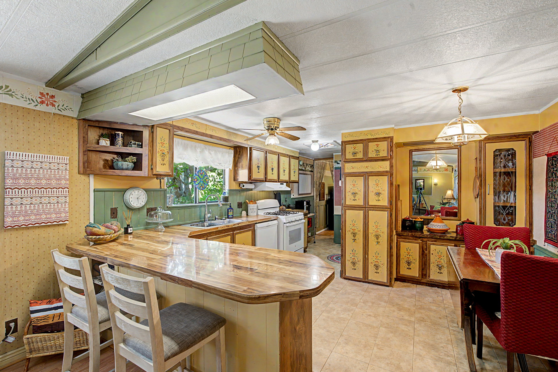 Kitchen featuring a built-in breakfast bar with a wood-finish countertop, white appliances, and a double basin sink