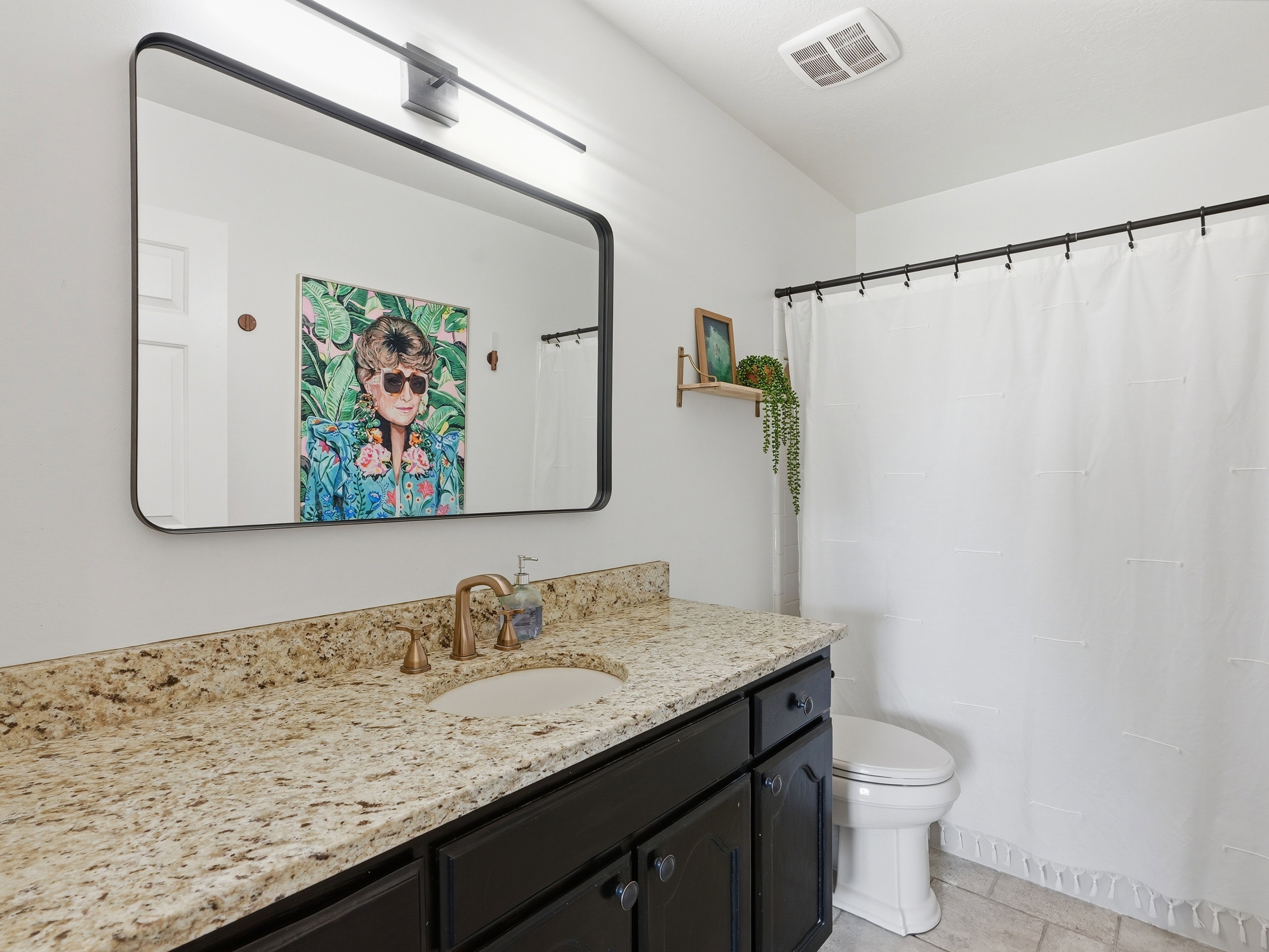 Bathroom vanity with granite-style countertop, undermount sink, and bronze-finish faucet