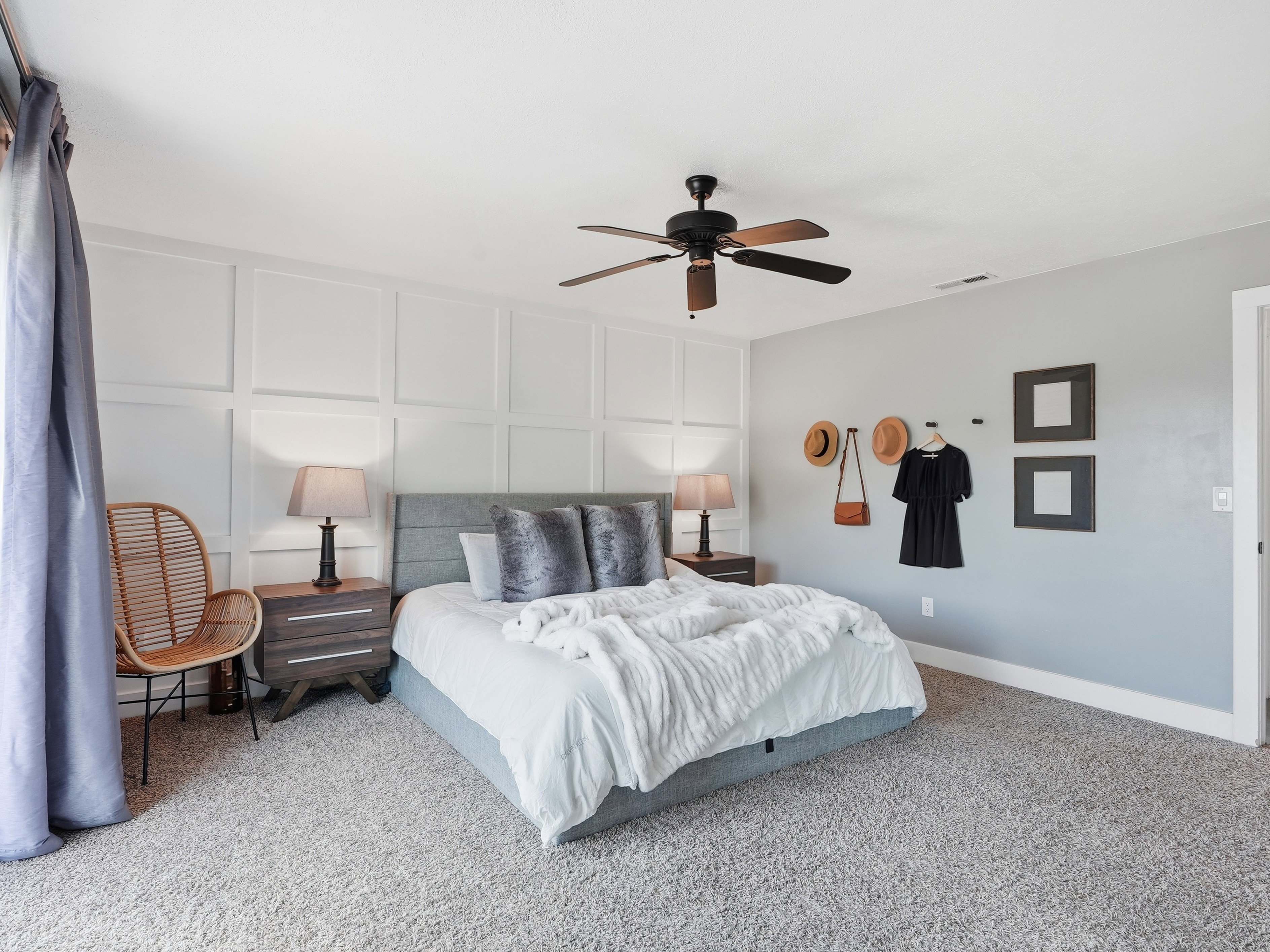 Bedroom featuring a paneled accent wall, a ceiling fan, and carpet flooring