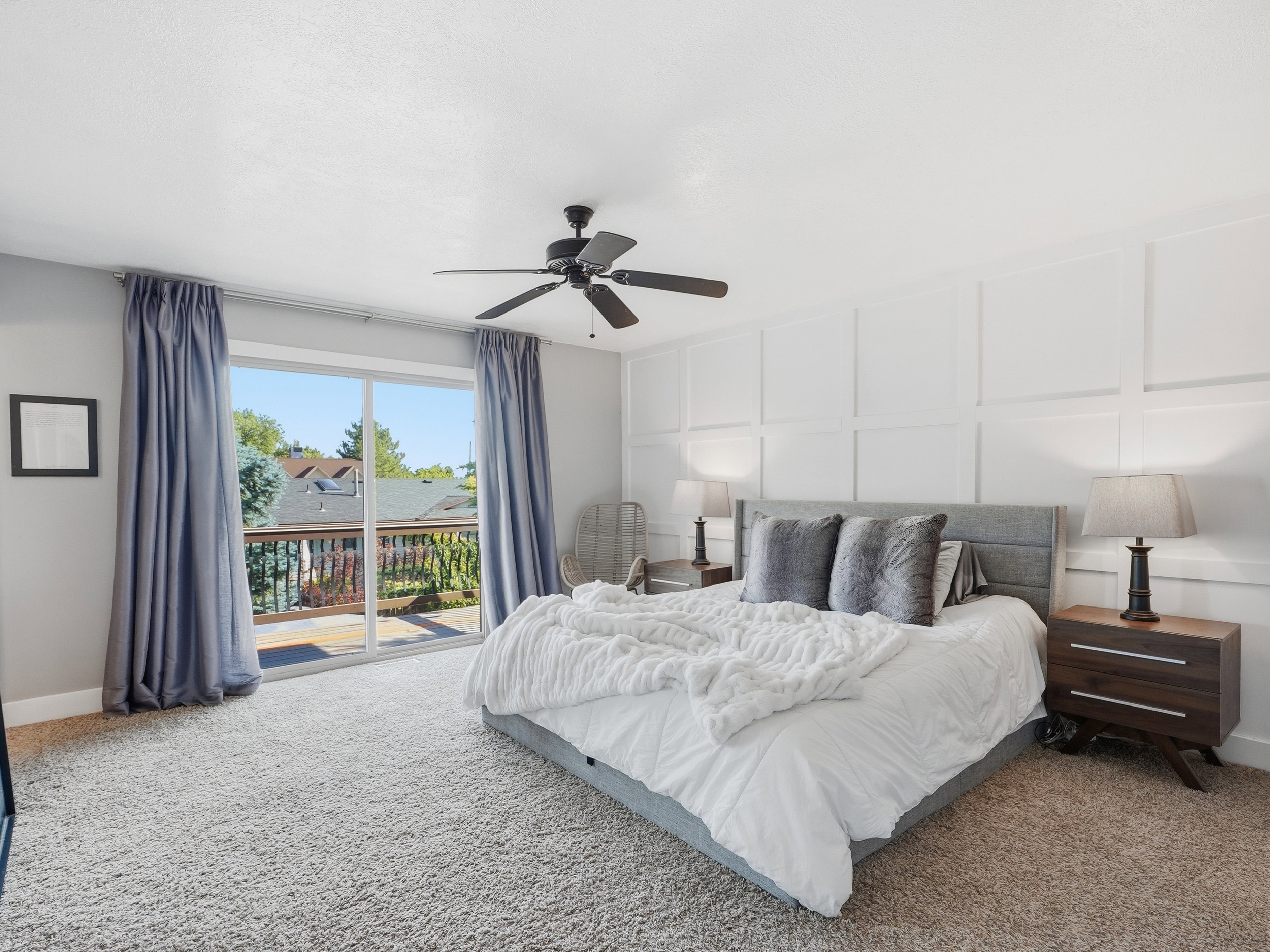 Room featuring a sliding glass door providing outdoor access, a paneled accent wall, a ceiling fan, and carpet flooring