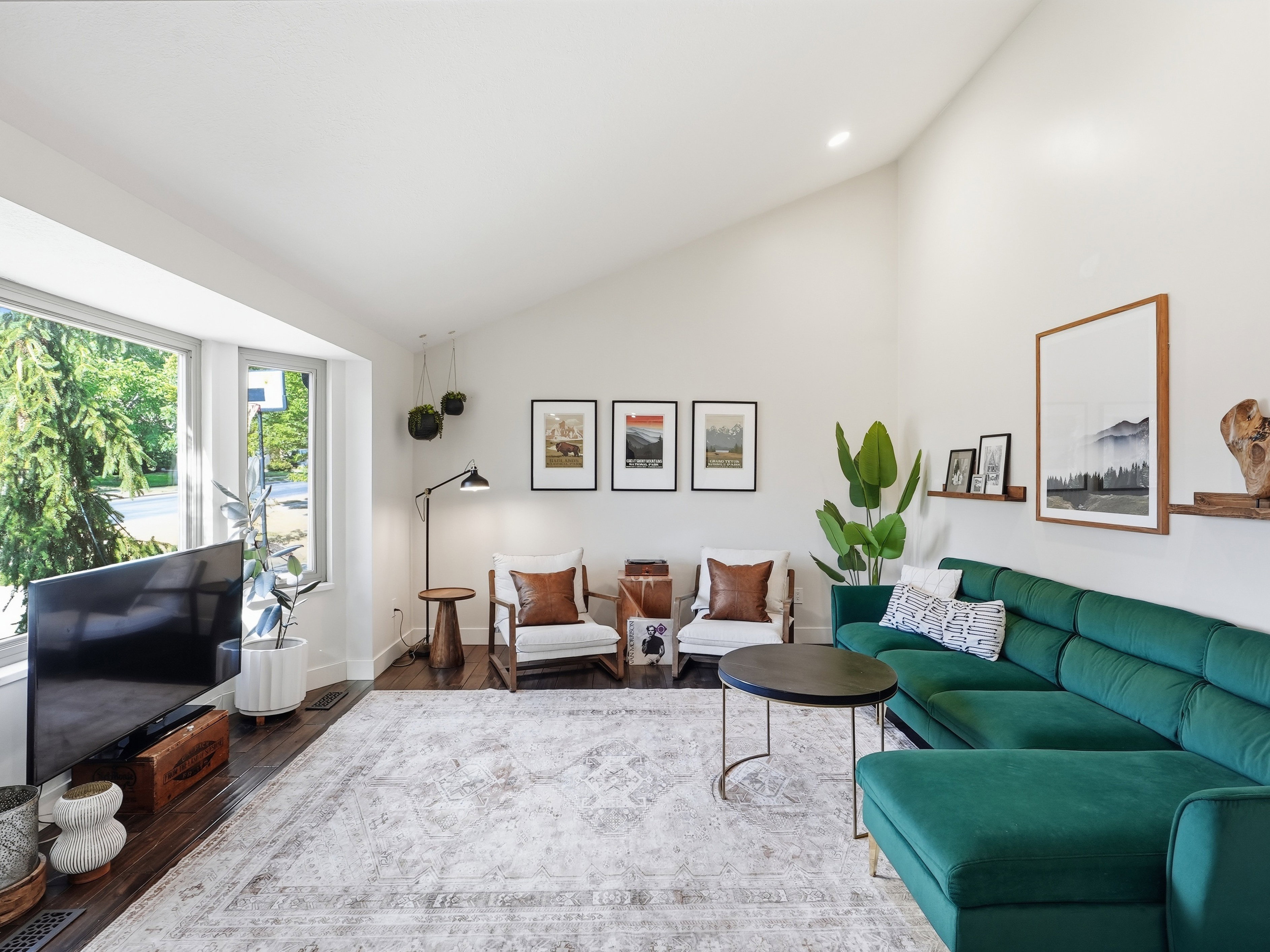 Spacious living area featuring high vaulted ceilings, expansive bay windows, rich wood-finish flooring, recessed lighting, and wall-mounted shelving