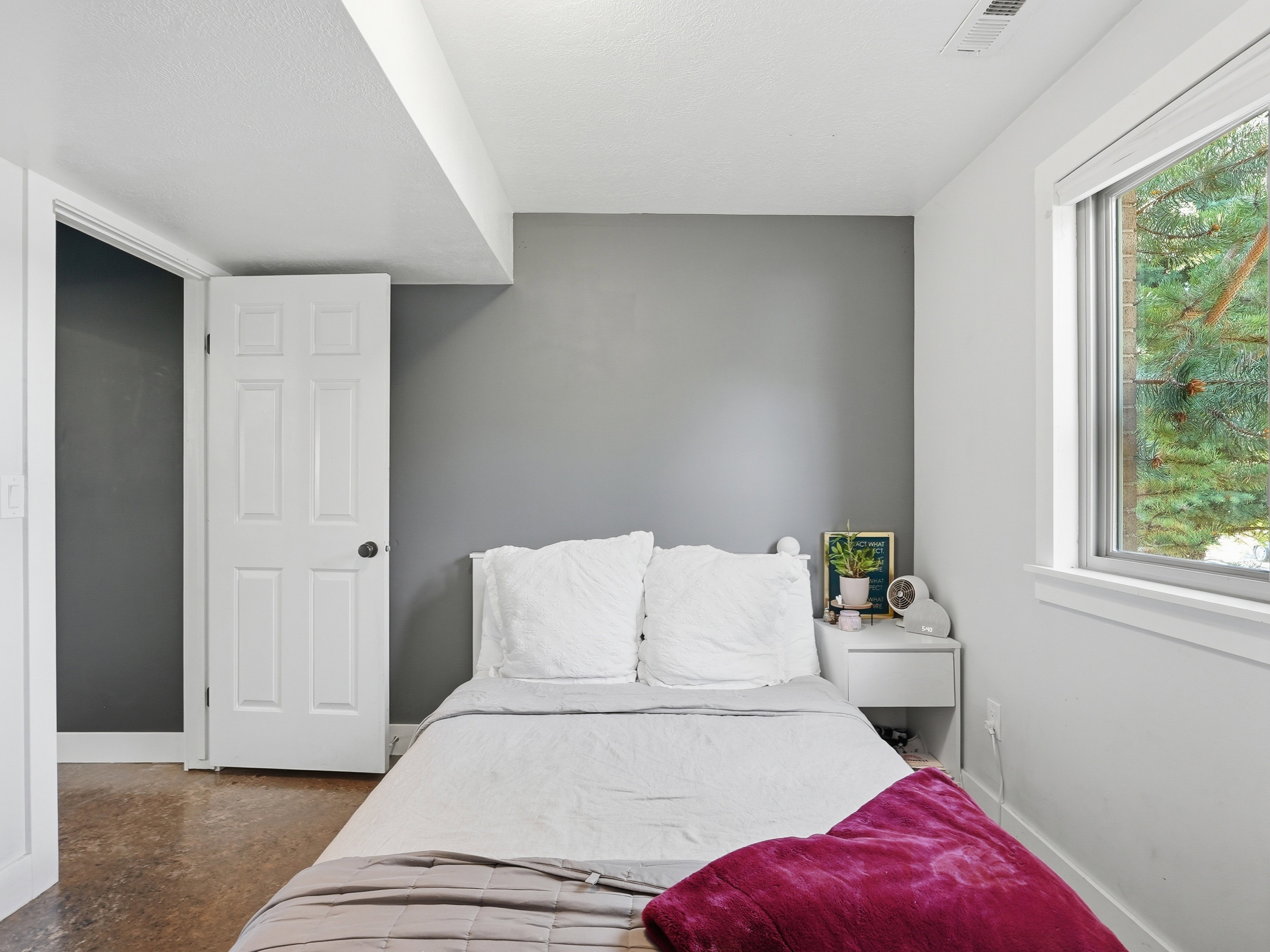 Room featuring a neutral grey accent wall, white trim, and a clear window